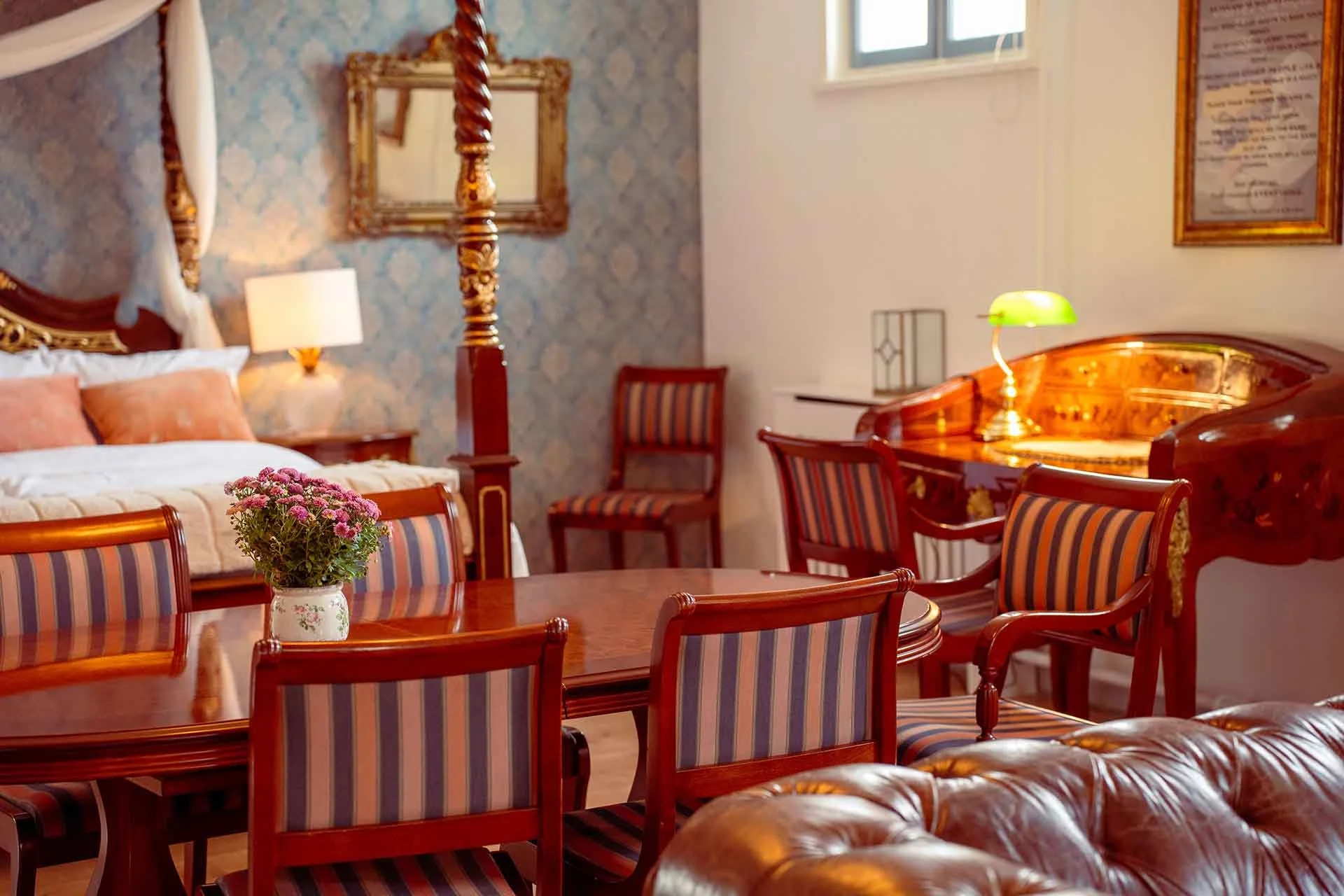 Forgyldt himmelseng, blå tapet, spisebord, Chesterfield sofa