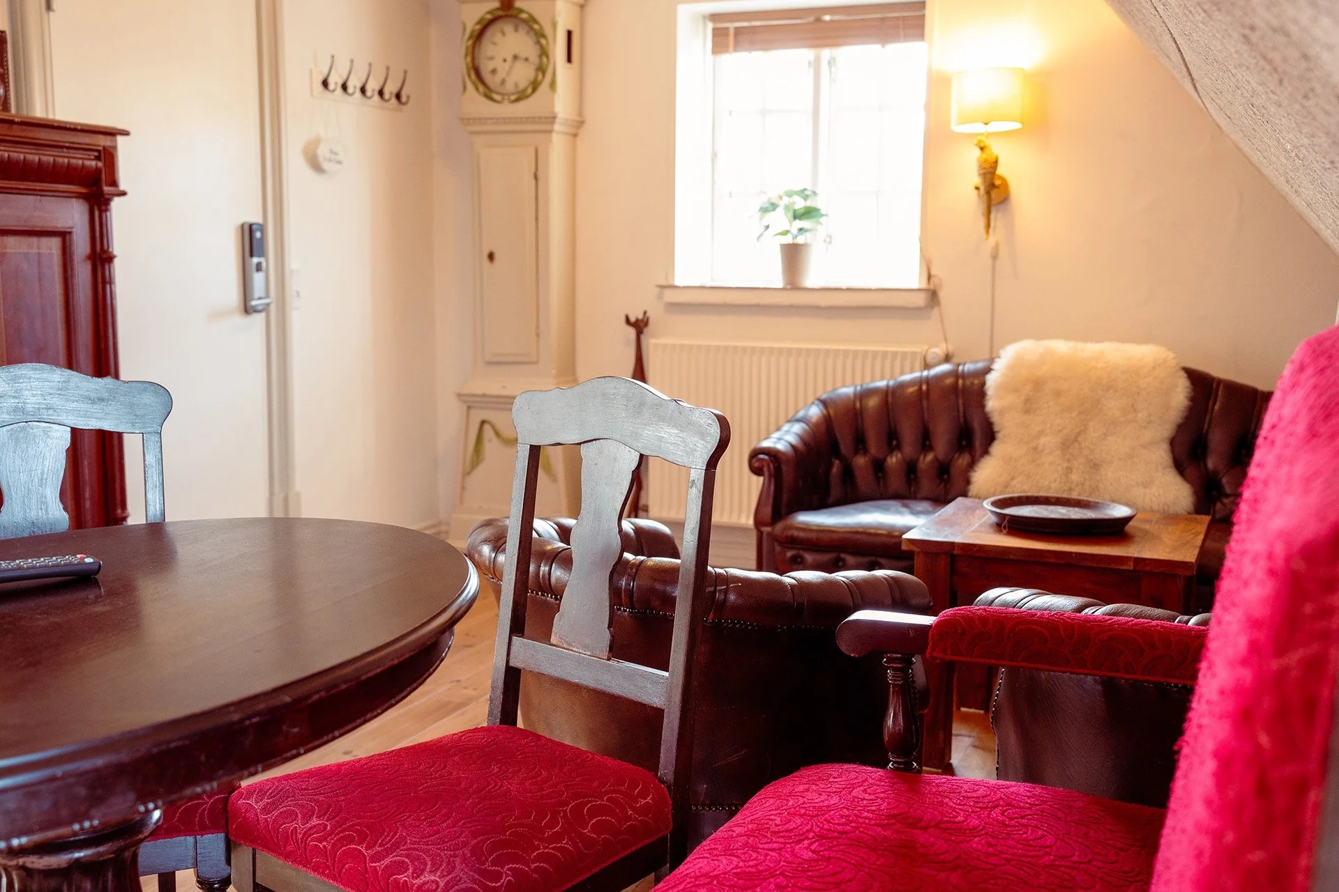 Røde stole, rundt bord, Chesterfield sofa, væglampe