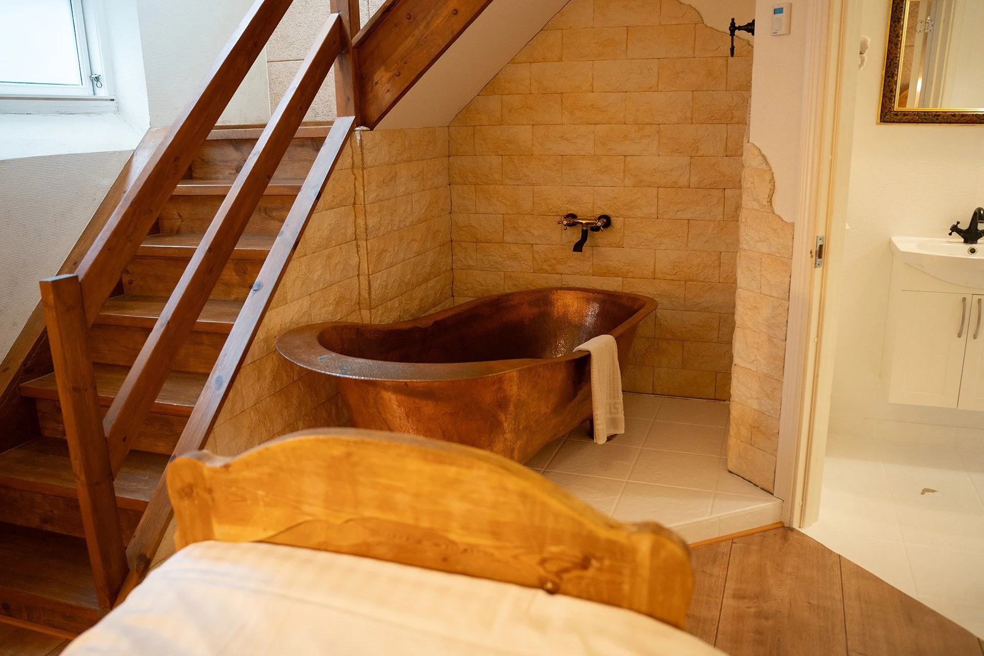Kobber badekar, loftstrappe, stenmur, træseng