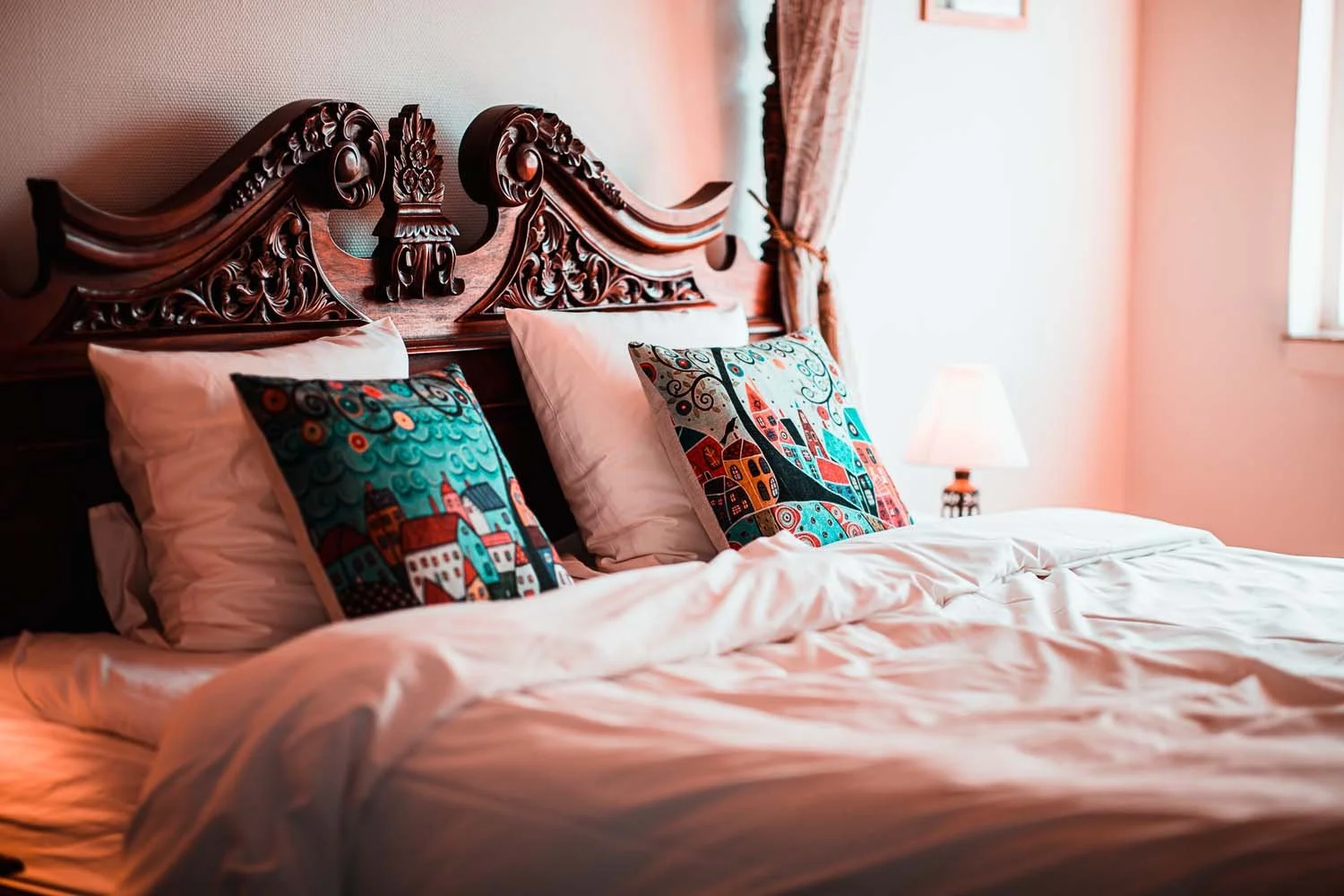 Antik sengegavl detalje, farverige puder, sengelampe