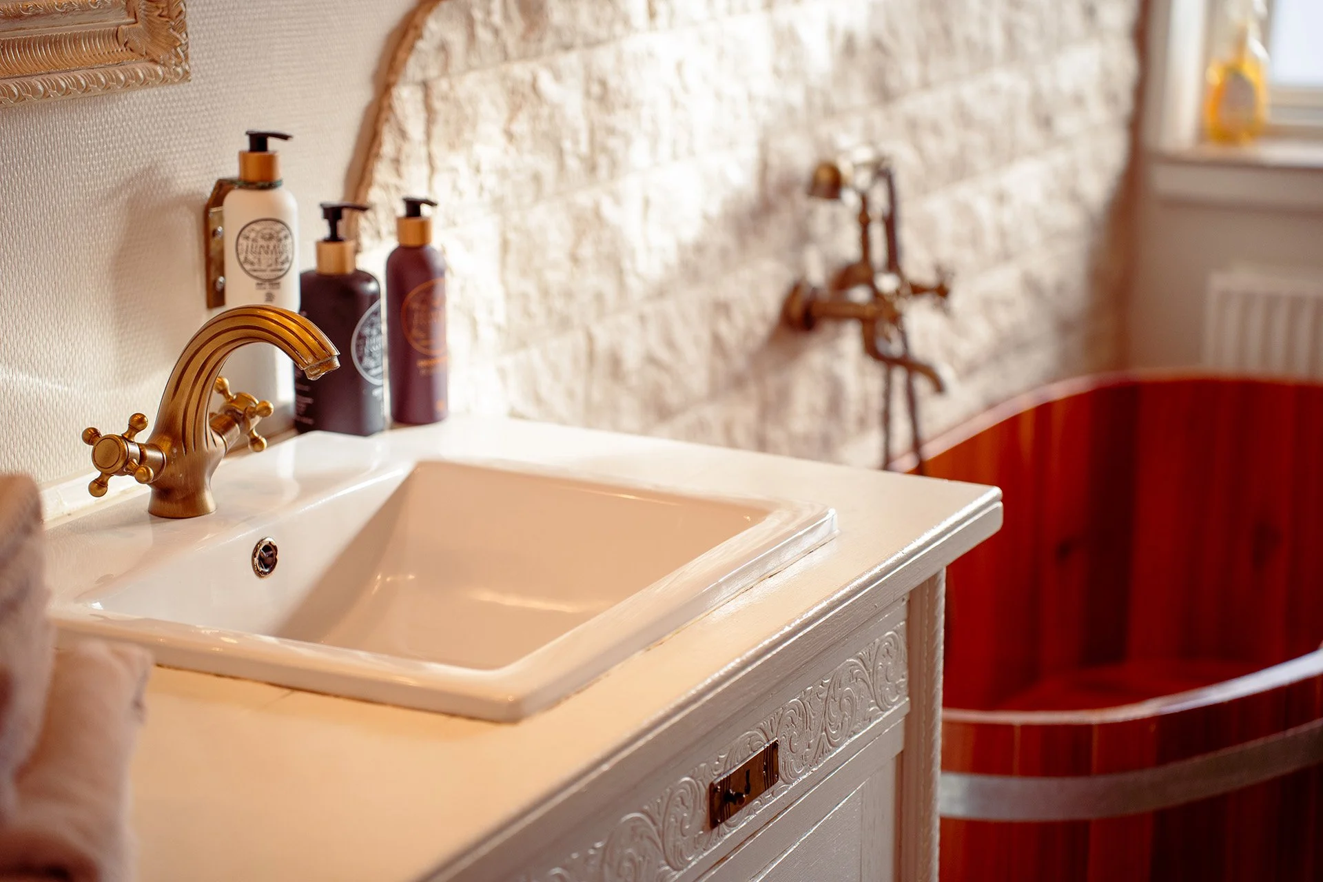 Badeværelse hvid vask guldfarvet armatur toiletartikler