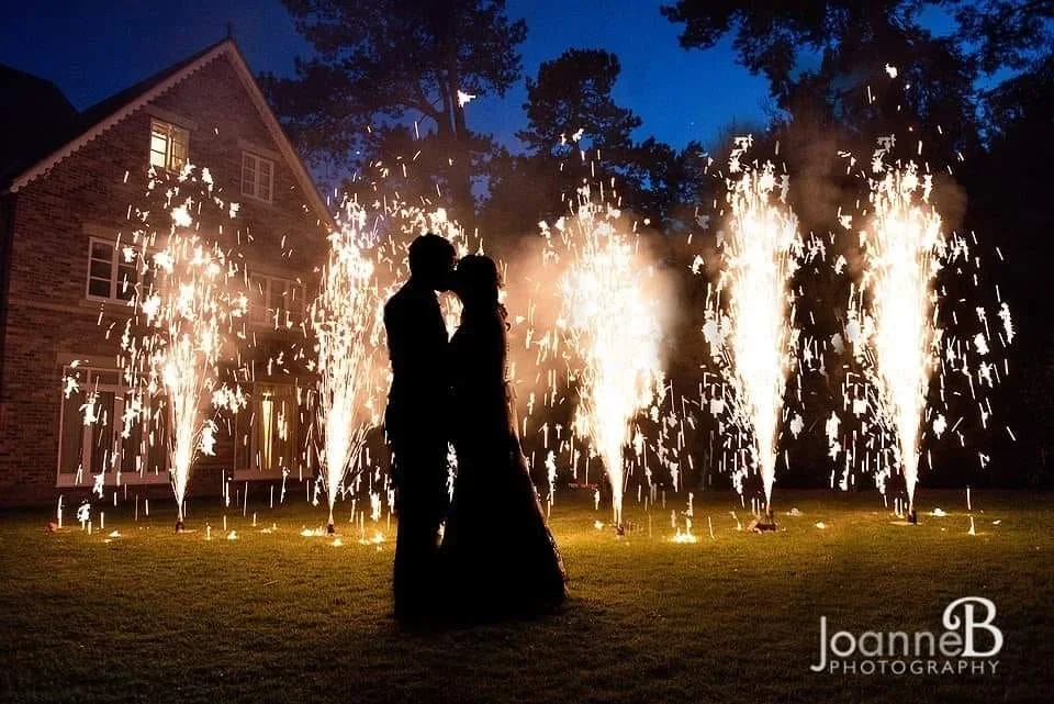 Silhouette of a couple kissing in front of fireworks display of fountains at night. Photo by JoanneB