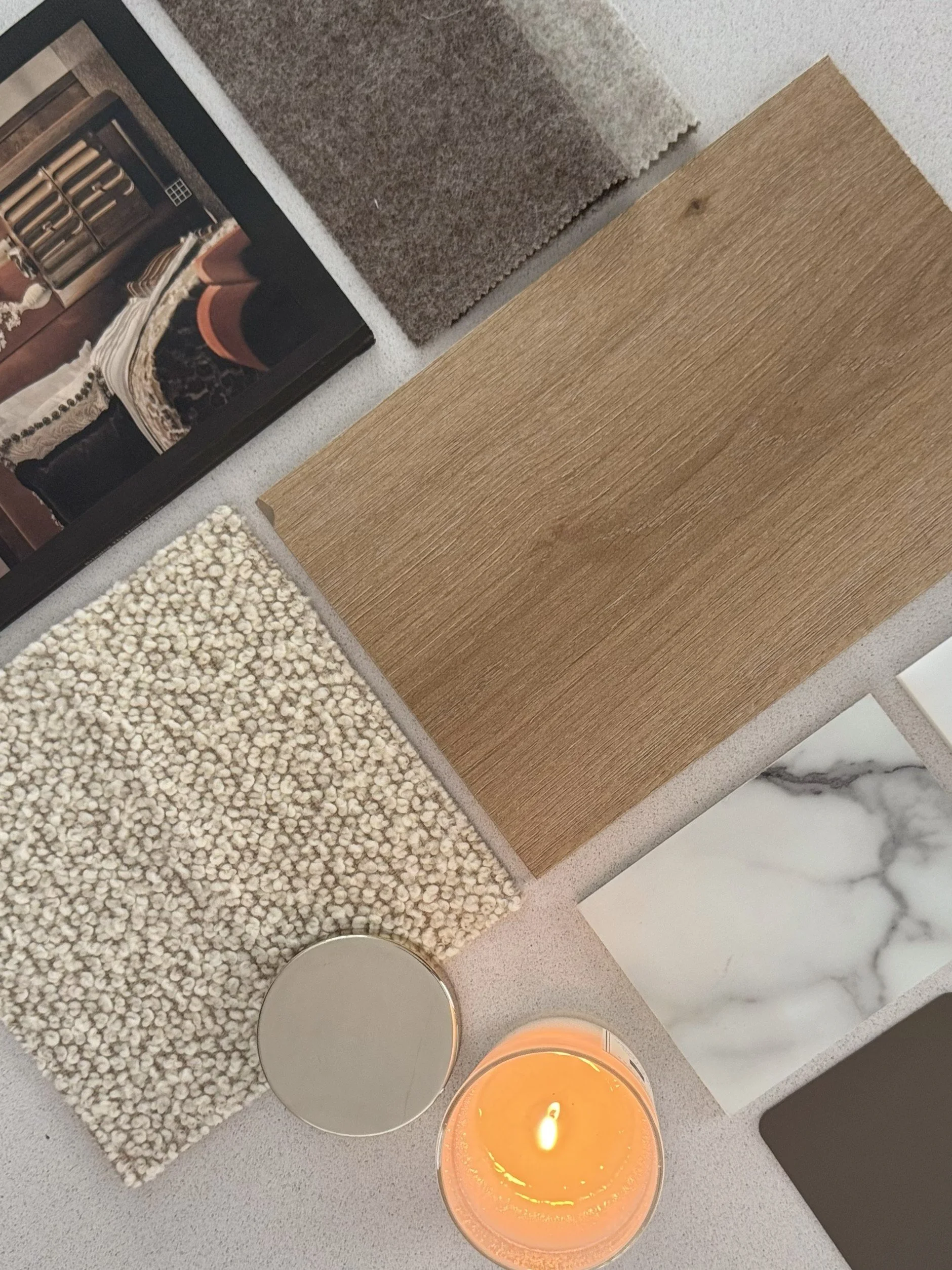 Sample of various flooring materials and colors including carpet, wood, and tile, along with a lit candle.