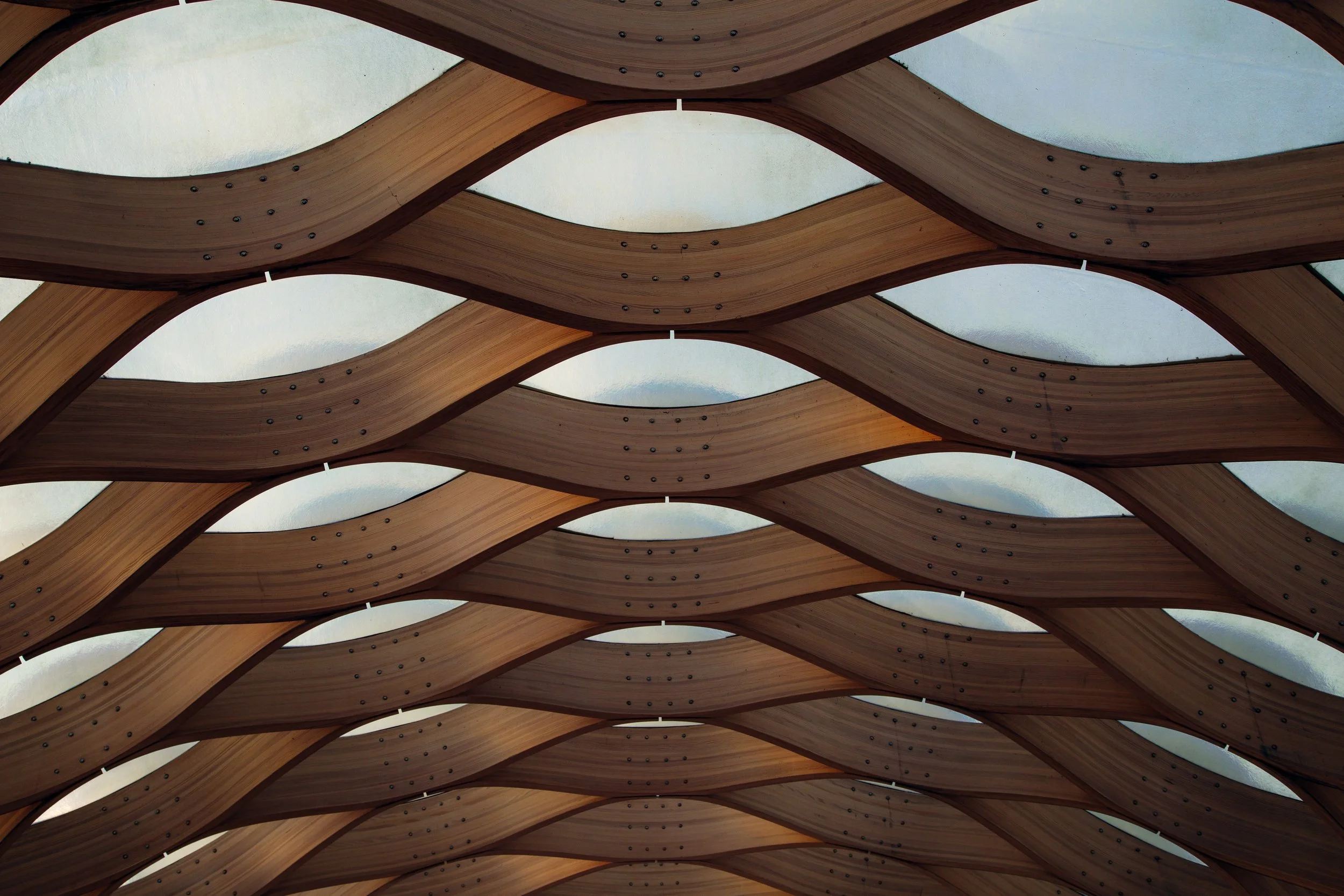 A modern architectural ceiling design with interwoven wooden beams and translucent panels.
