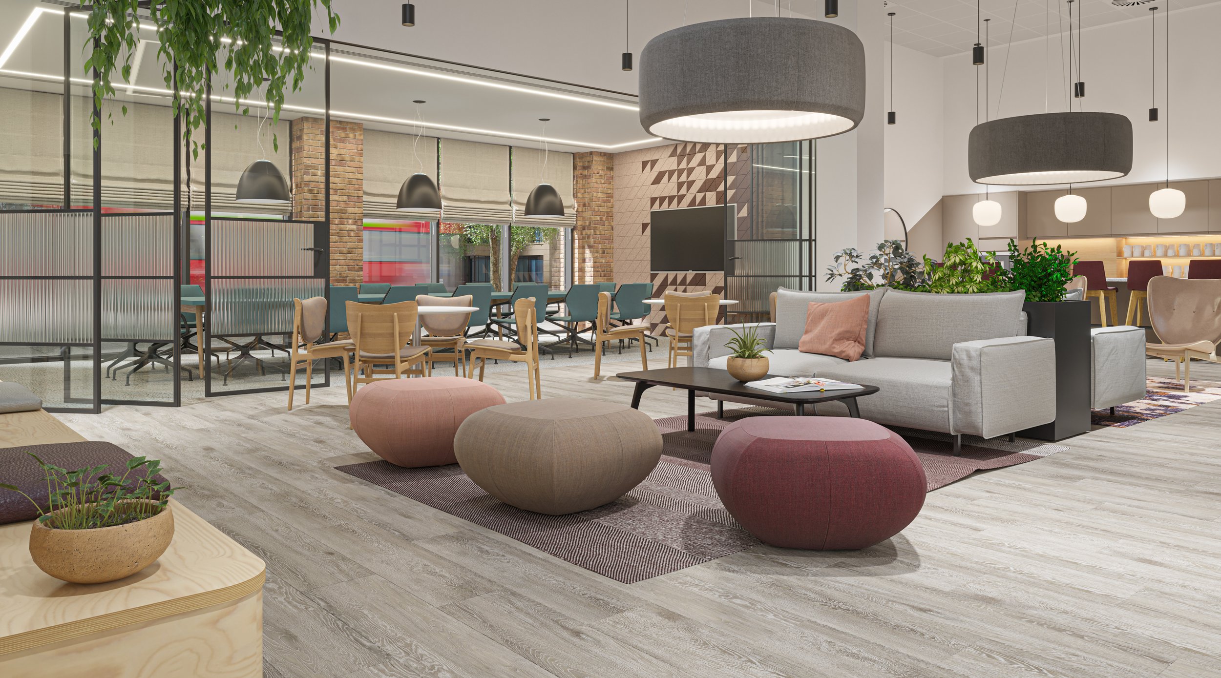 Modern office lounge area with a white sofa, pink and beige poufs, a black coffee table, and potted plants. In the background, there is a dining area with tables and chairs, large windows, and pendant lighting.