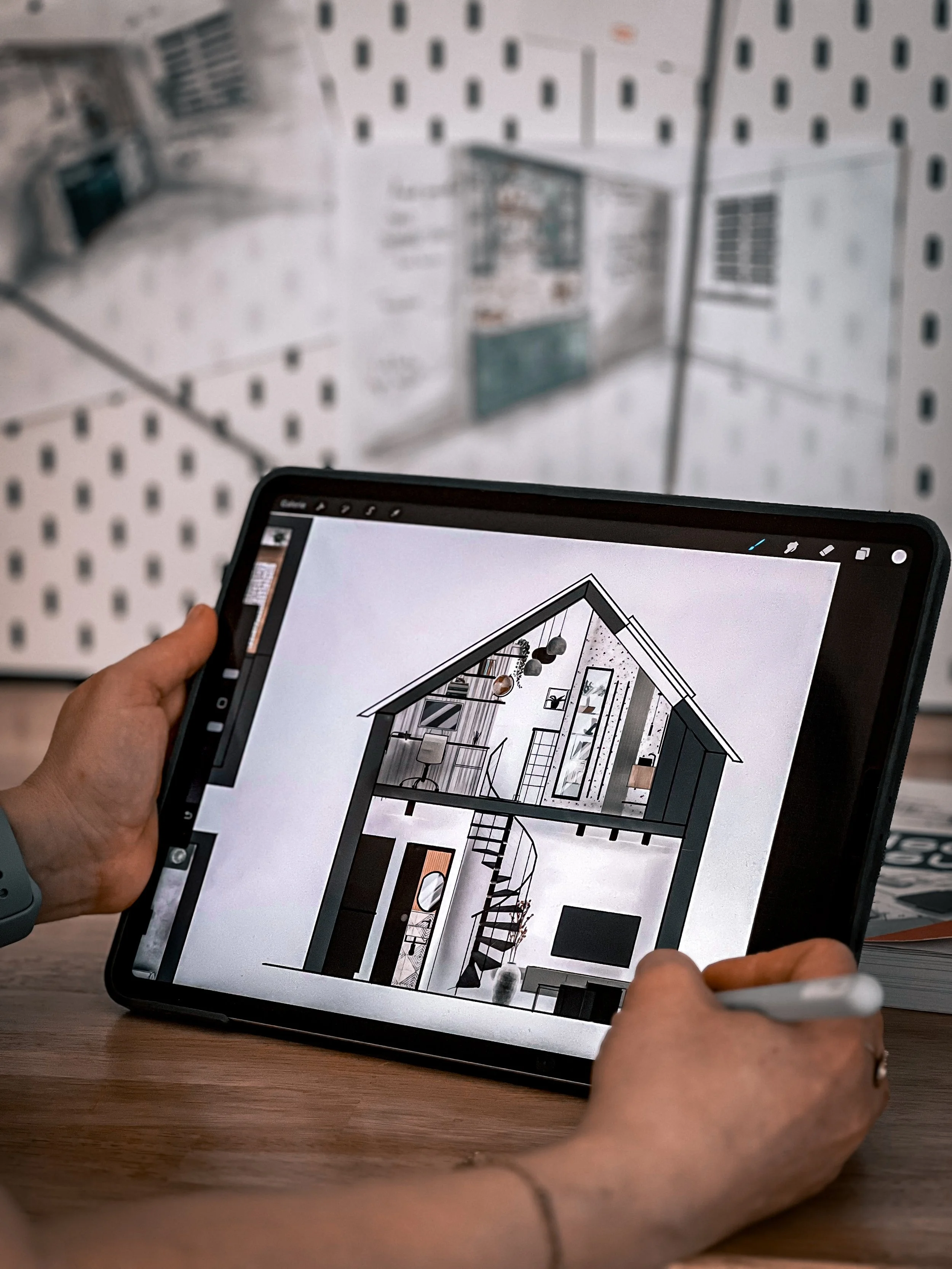 Un designer qui tient une tablette affichant un plan de maison en 3D, dans un magasin de décoration ou d'ameublement.