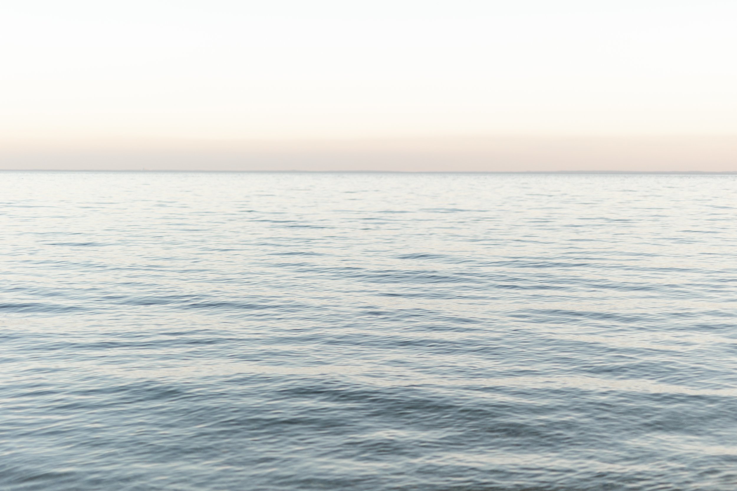 Calm ocean water with gentle ripples on the surface, under a clear sky.