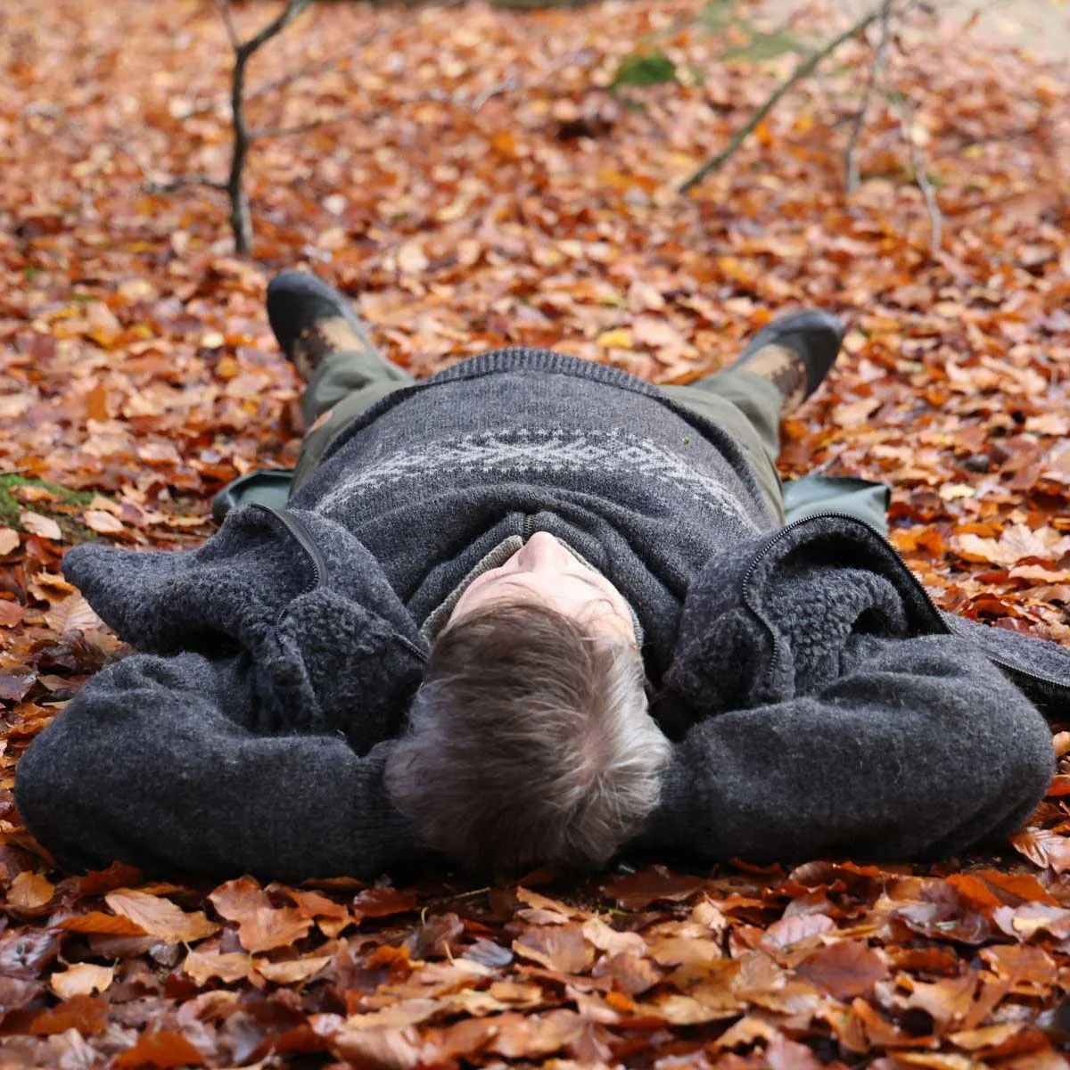 Person ligger på ryggen og mærker alle fordelene ved natureterapi og sansebad.