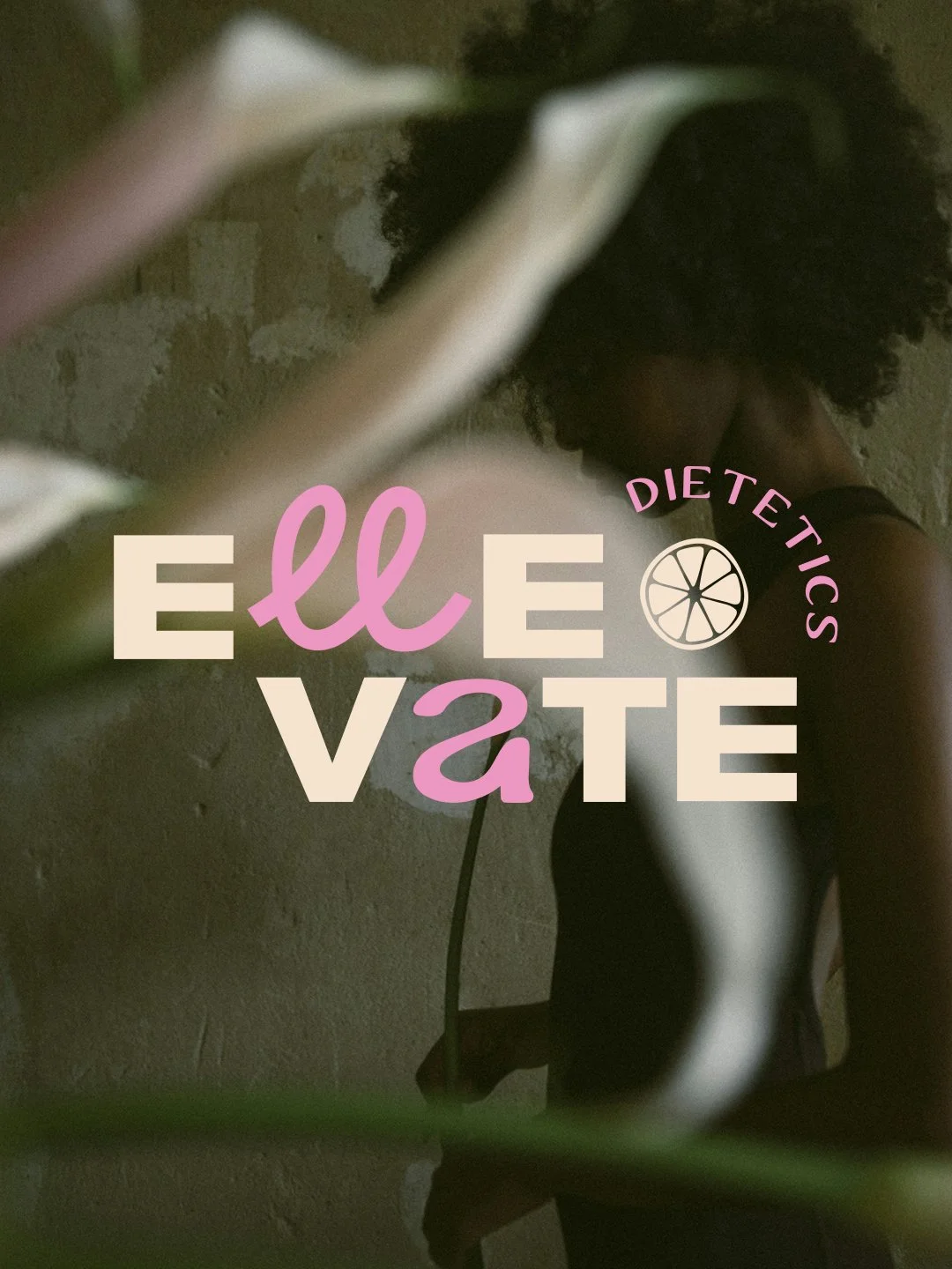 A woman with curly hair is sitting on the floor against a textured wall, partially obscured by blurred foreground object. Overlaid text reads 'Eat Ele VATE' with 'ell' and 'a' in pink, and a circular icon with a lemon slice and the words 'Dietetics' in pink.