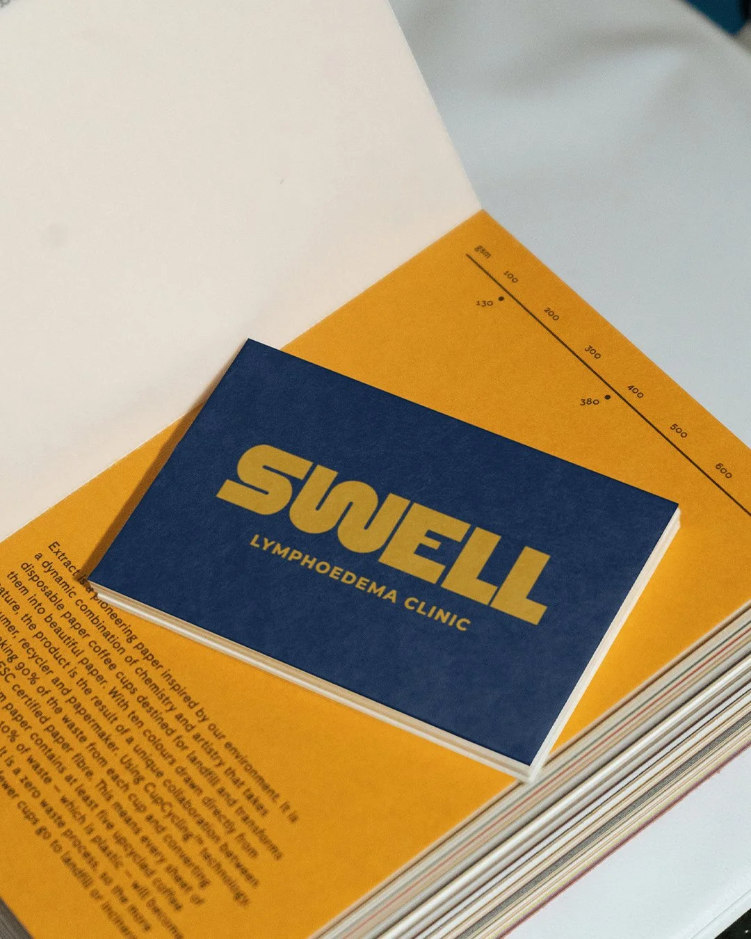 A pamphlet or booklet with a blue cover titled 'SNUEL LYMPOEDEMA CLINIC' placed on top of a yellow paper with printed text and a black measurement scale.