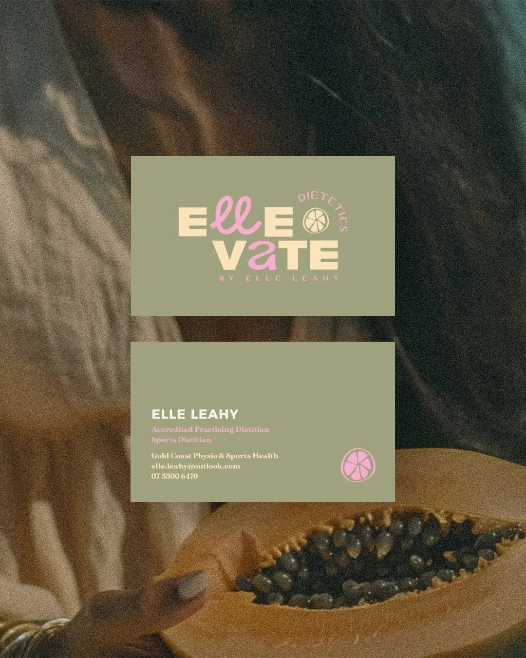 Business card for Elle Leahy, a dietitian specializing in sports nutrition, featuring a green background, pink and beige text, and a citrus slice logo, held in front of a papaya with black seeds.