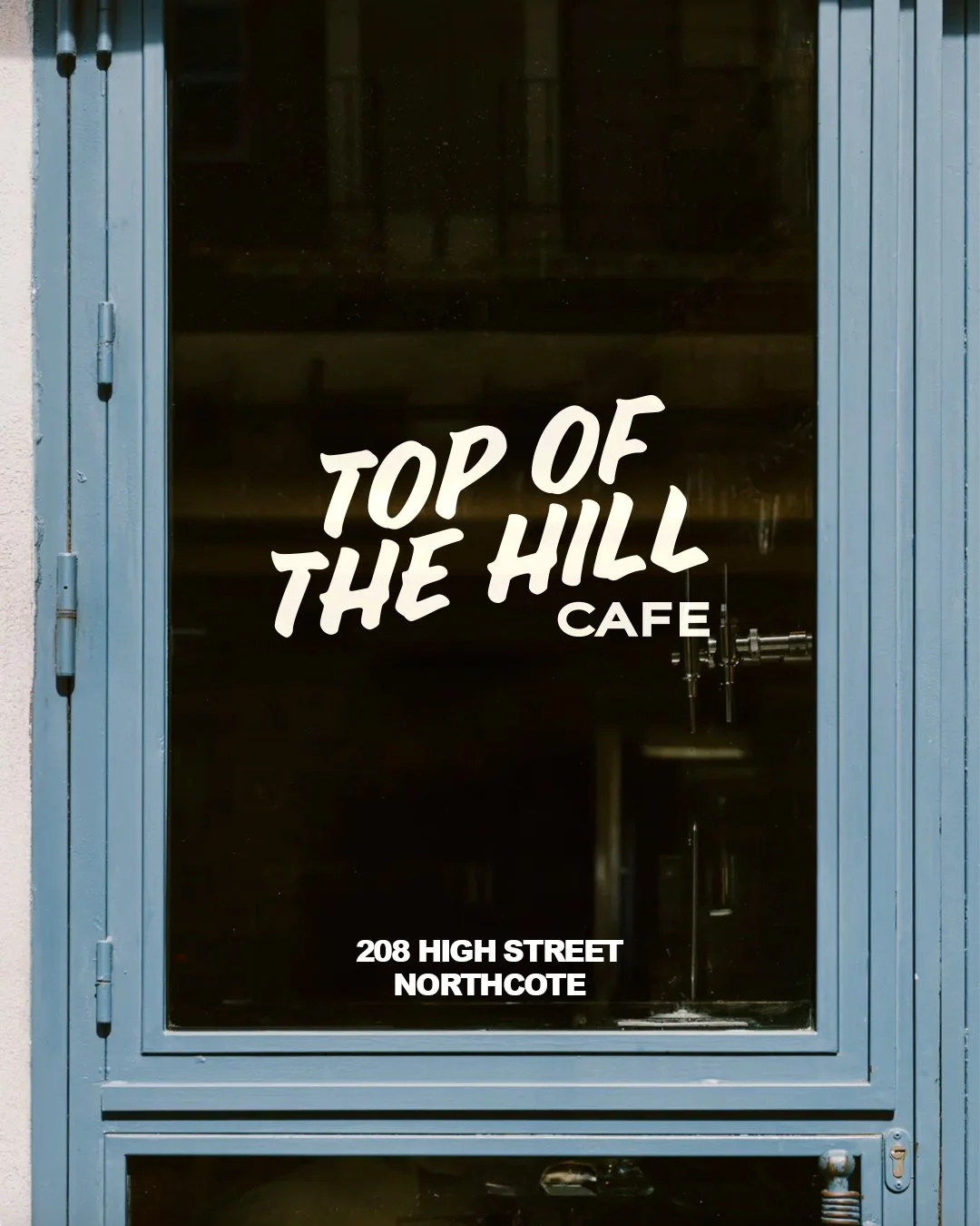 Sign on a glass door for Top of the Hill Cafe at 208 High Street, Northcote.