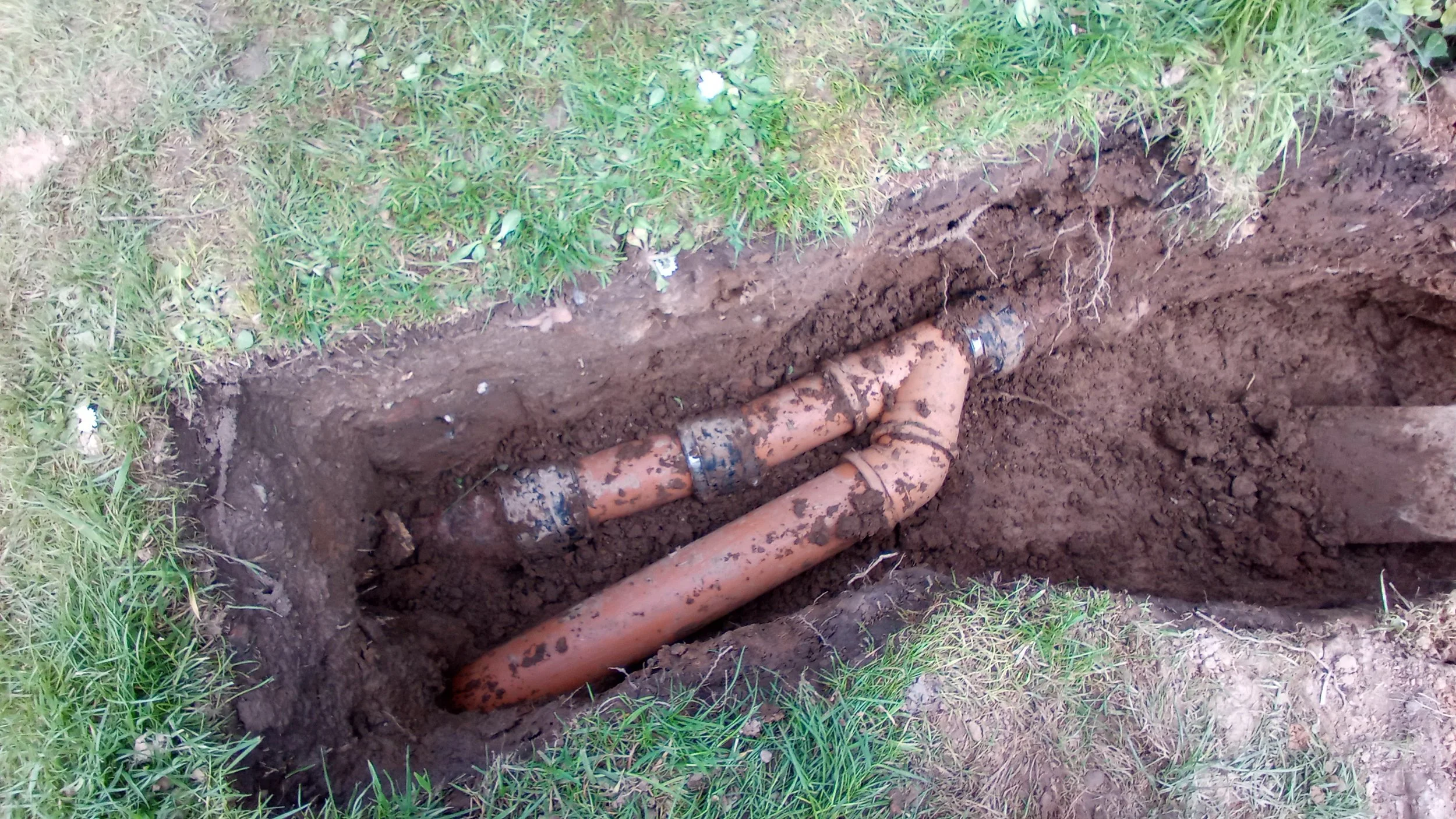Underground water pipes being repaired or installed in a grassy area.