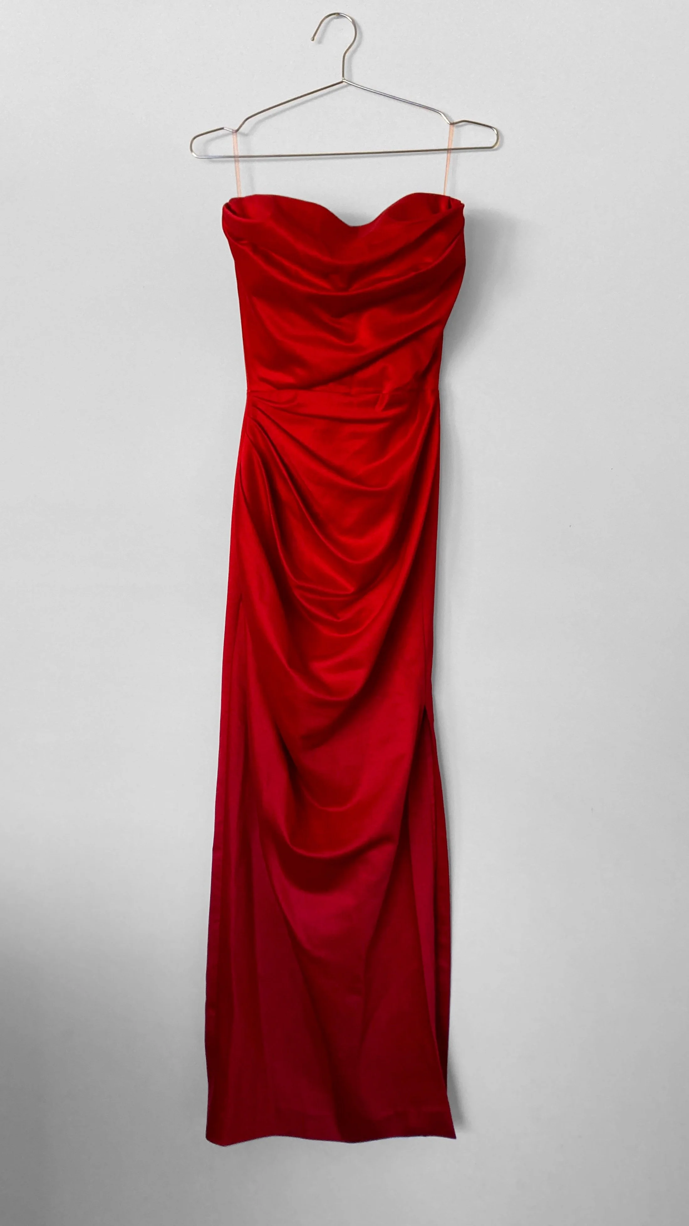 Full length view of a strapless red evening gown. It features soft draping over the bodice and hips.