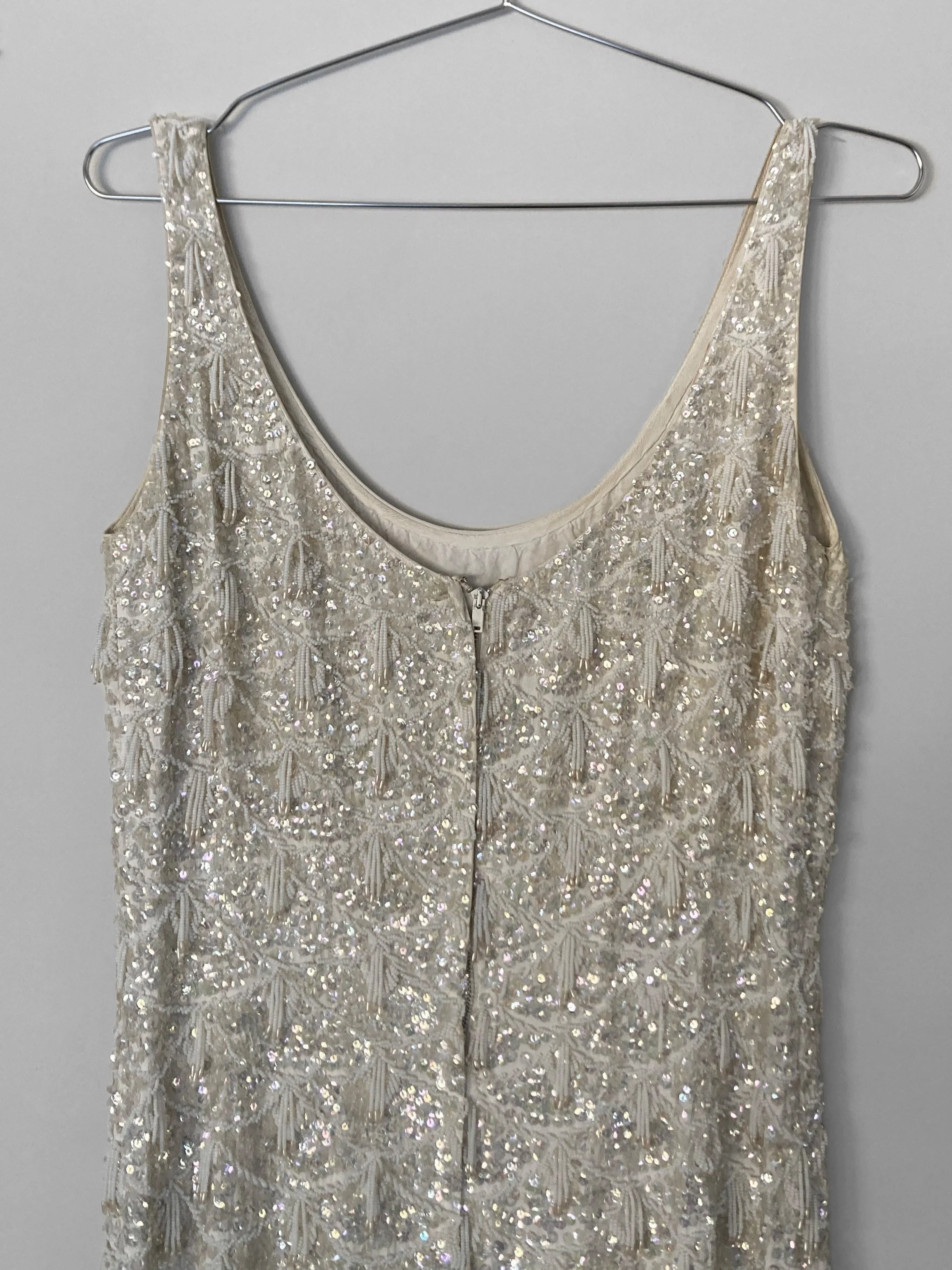 Close up back view of a hand beaded gown, with a centre back metal zip closure.