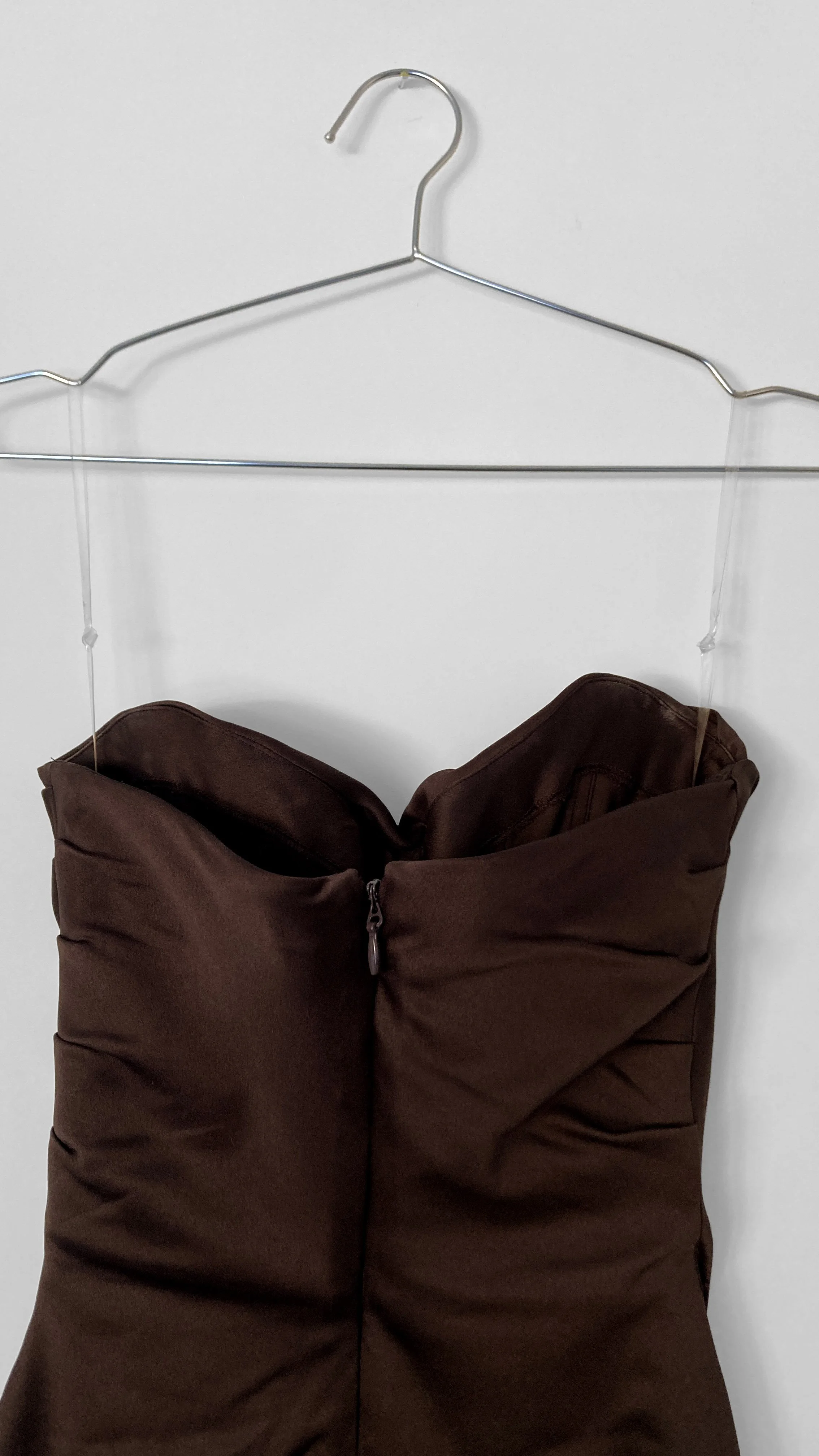 Close up image of the back of a strapless chocolate coloured cocktail dress with centre back zip closure.