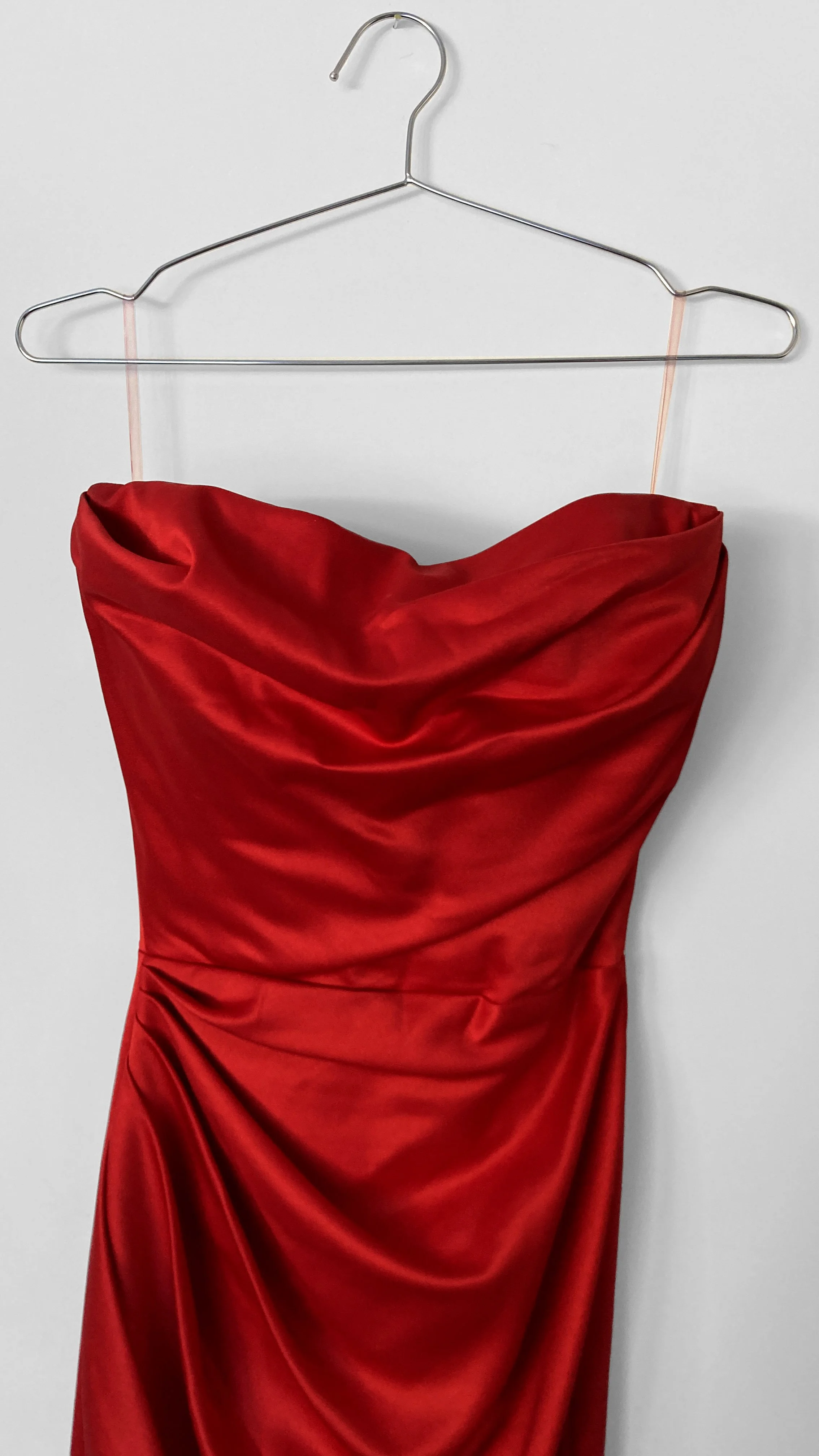 Close up image of a classic strapless Hollywood red evening gown, with soft draping over the bust.