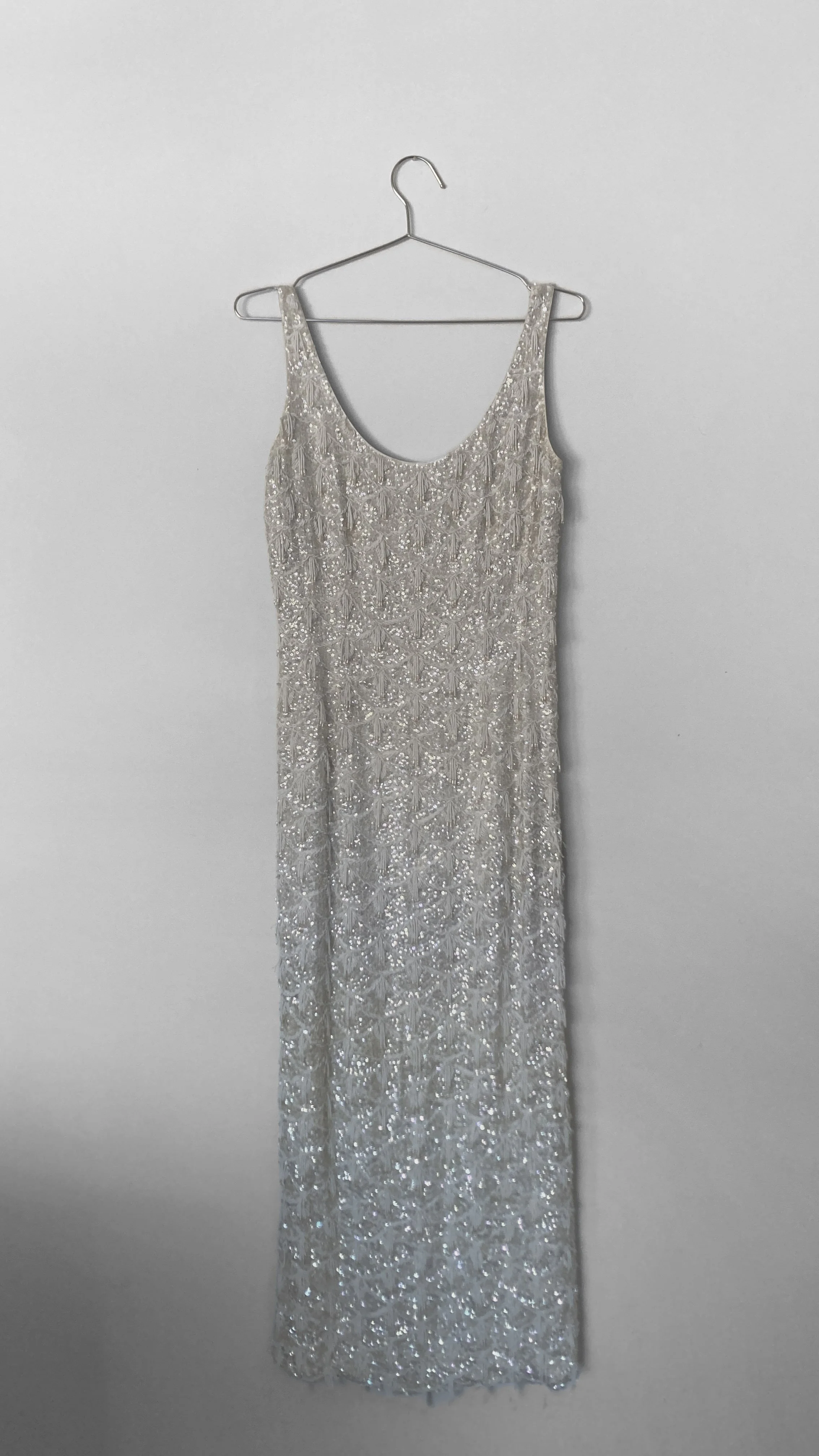 Full length view of an ivory coloured hand beaded evening gown. It is floor length, sleeveless and has a scoop neck line.