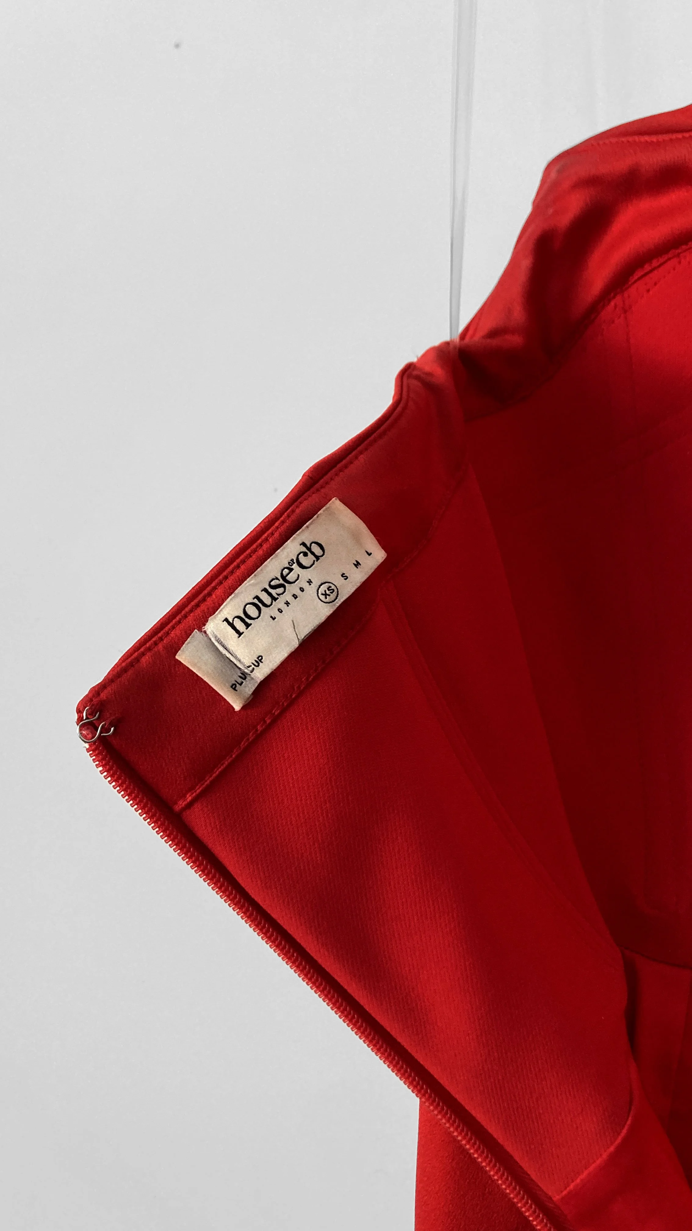 Close up internal view of the centre back zip closure, hook and eye, and "House of CB" label, that shows size "Plus Cup XS"