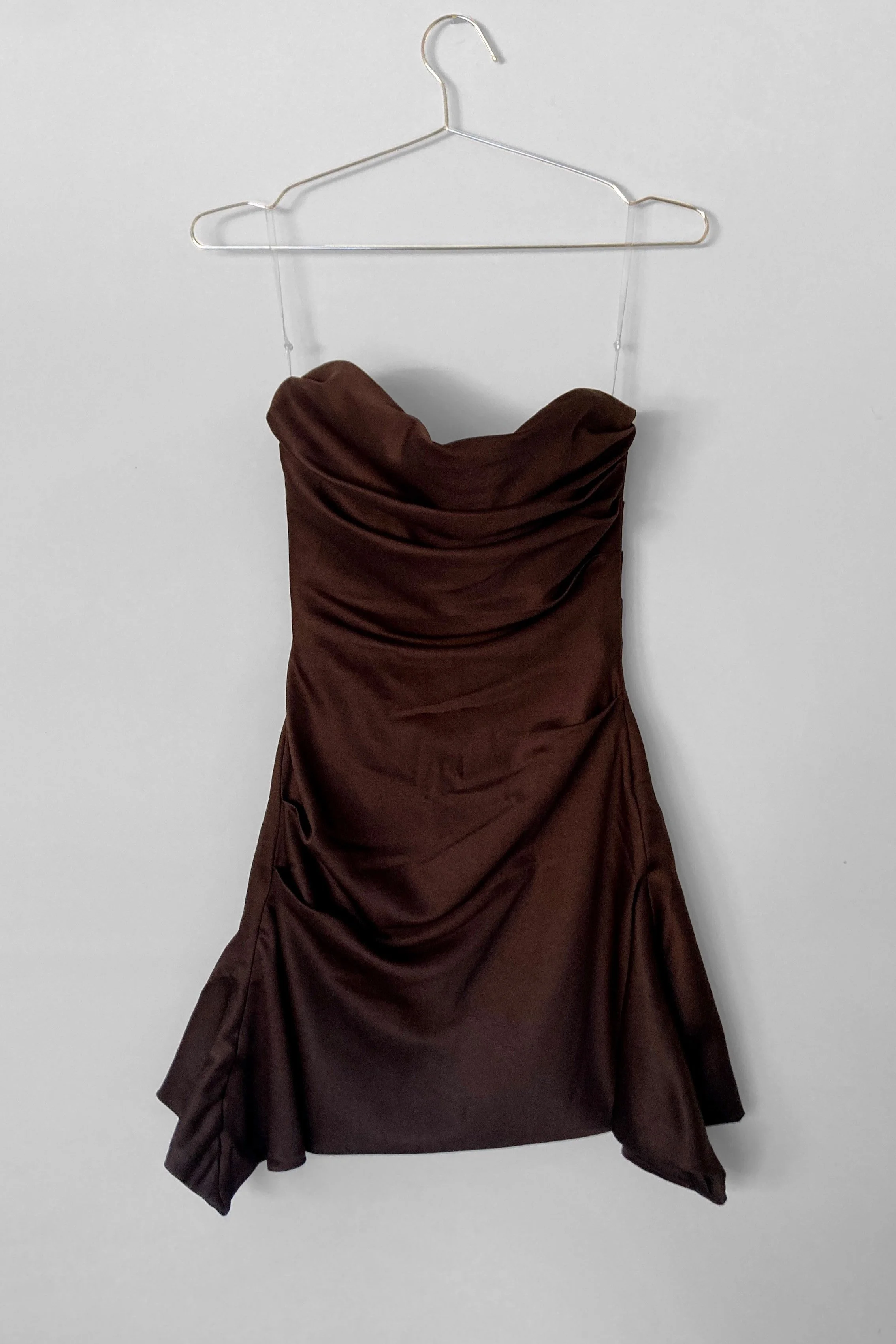 Full length view of a mini chocolate coloured cocktail dress, with soft draping over the bust, and the hem finishes longer at the sides, creating a waterfall effect.