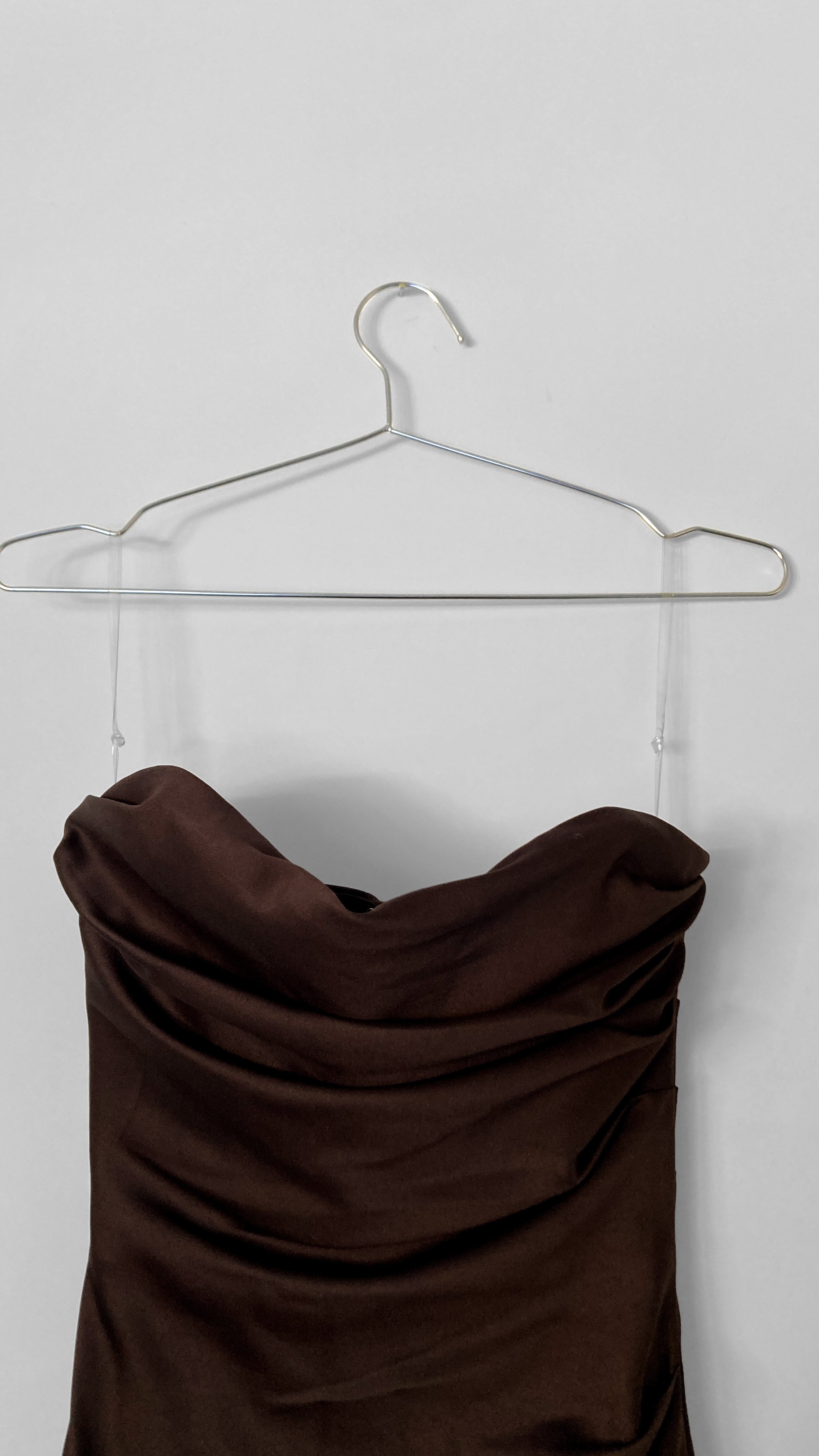 Close up image of a strapless chocolate coloured cocktail dress with soft draping over the bust.