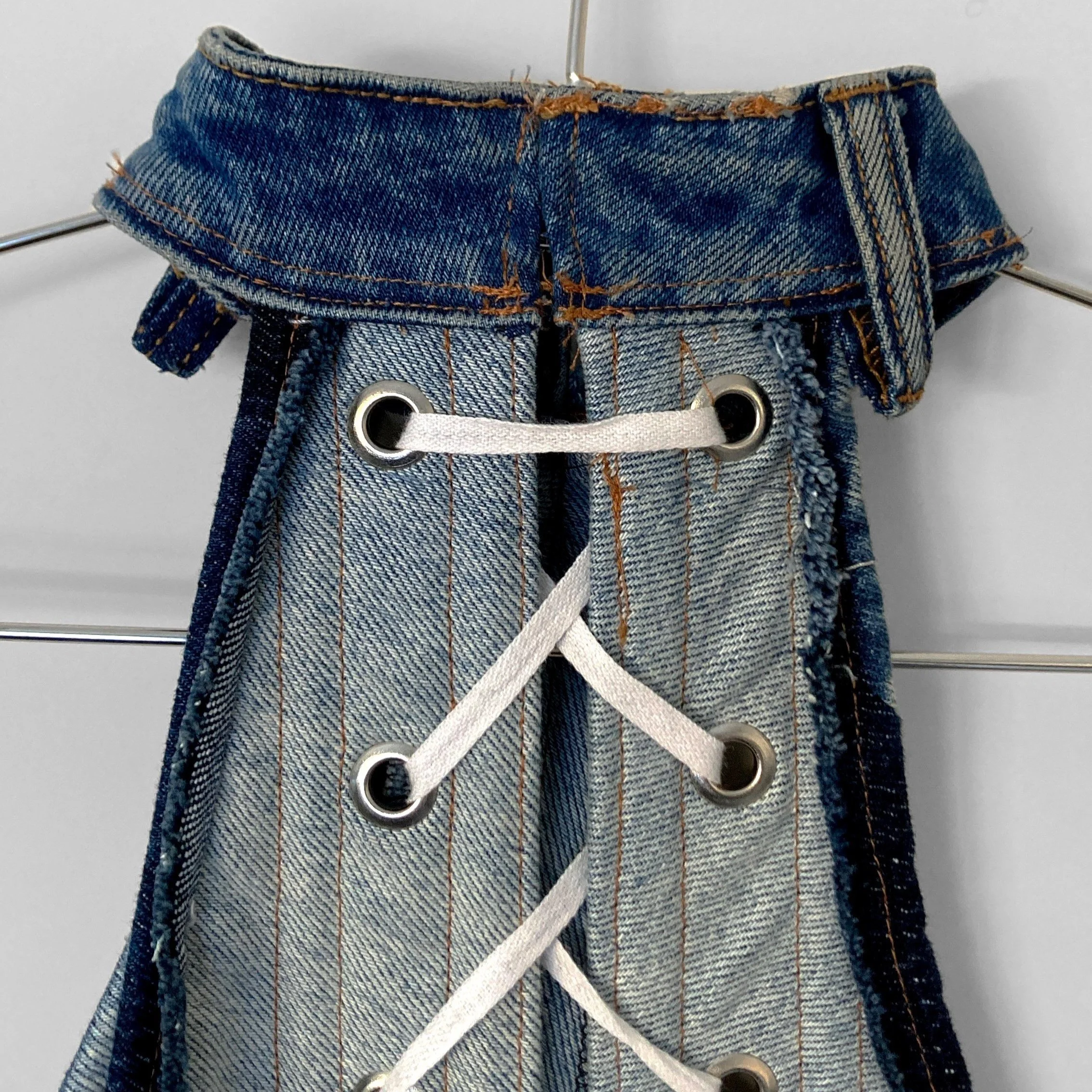 Close up back view of the upcycled jeans boned bodice collar, where there is a hidden hook and eye fastening, and it shows a belt loop from the original jeans waistband. It also shows the boning channels and the lace up corset style back.