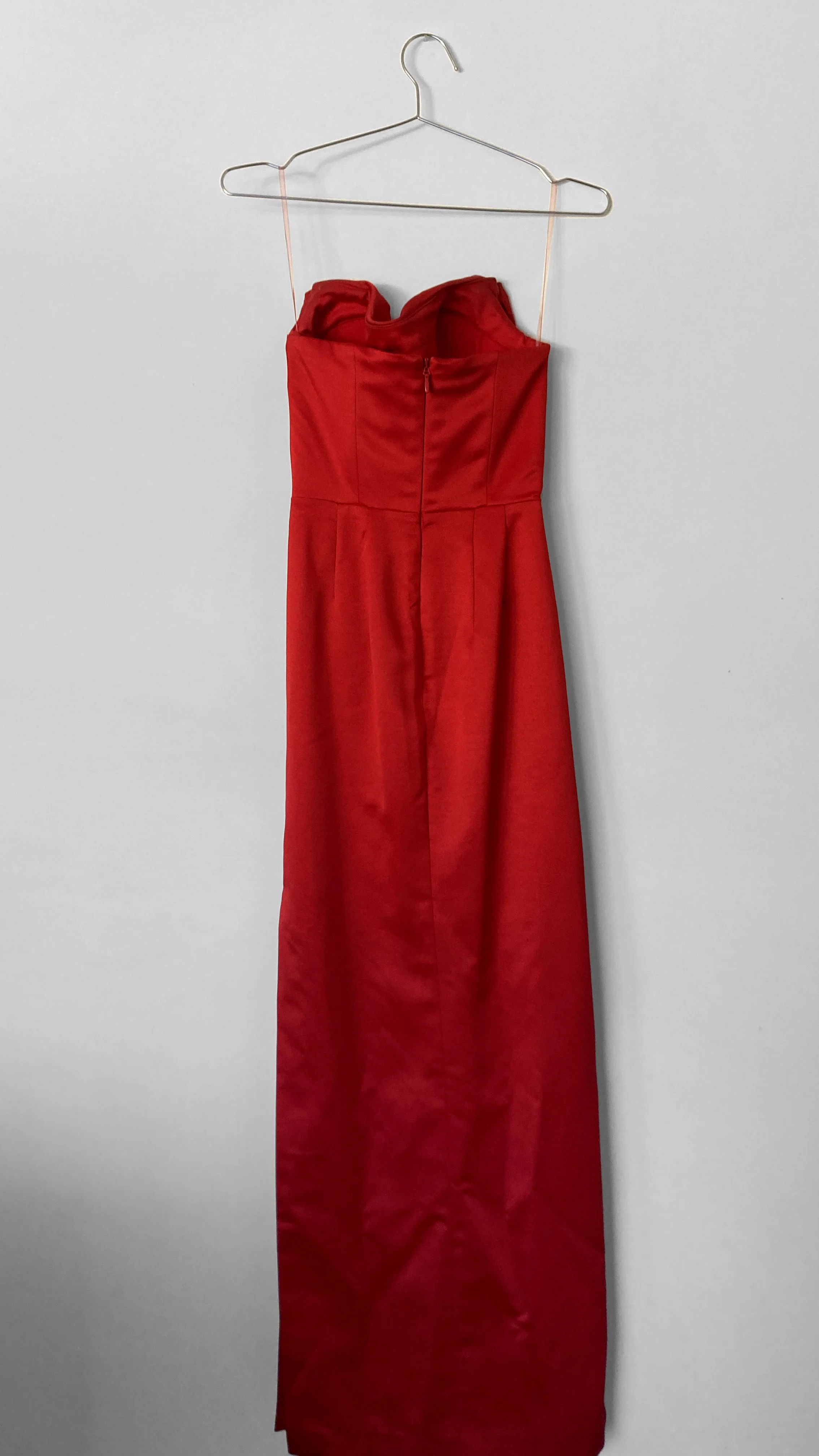 Full length back view of a strapless red evening gown. It features back darts and a centre back zip closure.