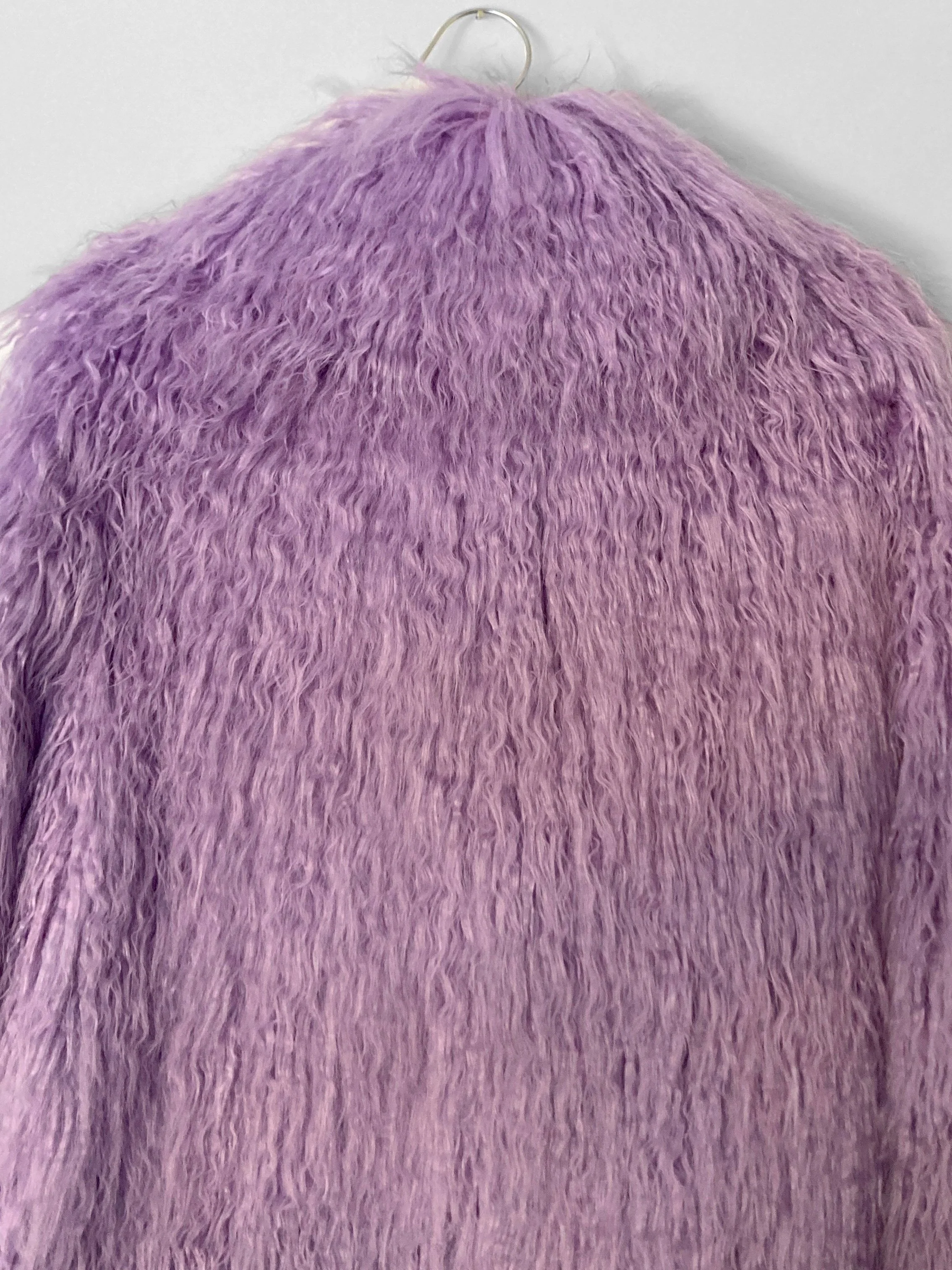 Close up back view of a lilac-purple hip length faux fur jacket.