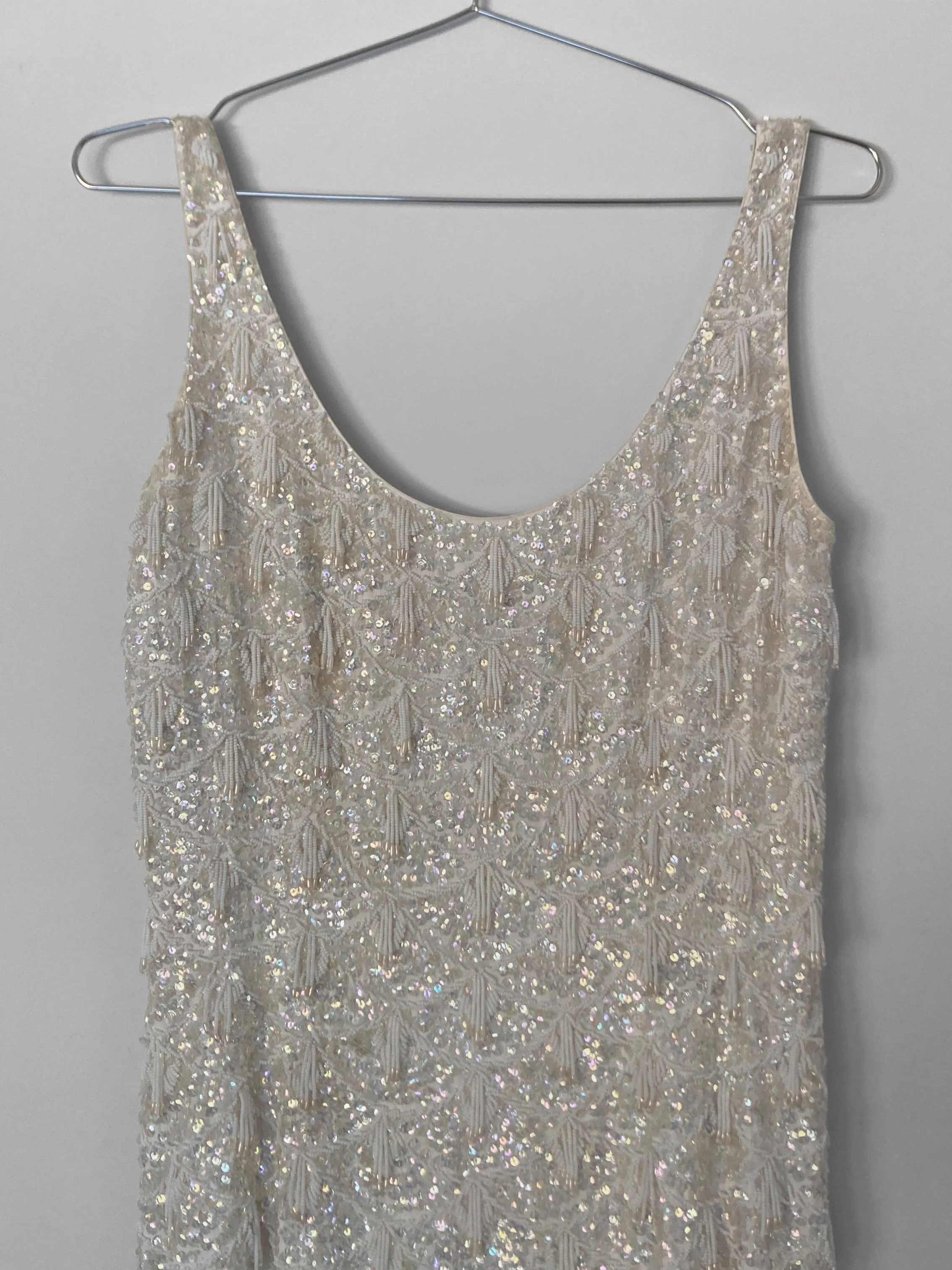 Close up image of the scoop neckline and straps of a handbeaded 1960s evening gown.