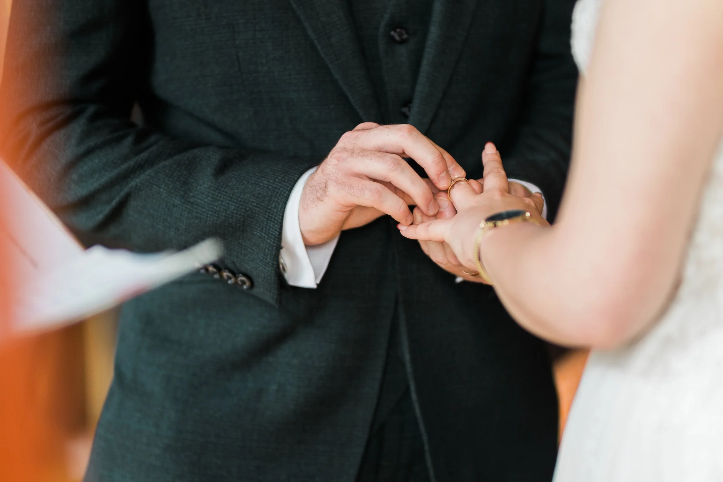 A groom places a wedding ring on the bride's finger during a wedding ceremony.