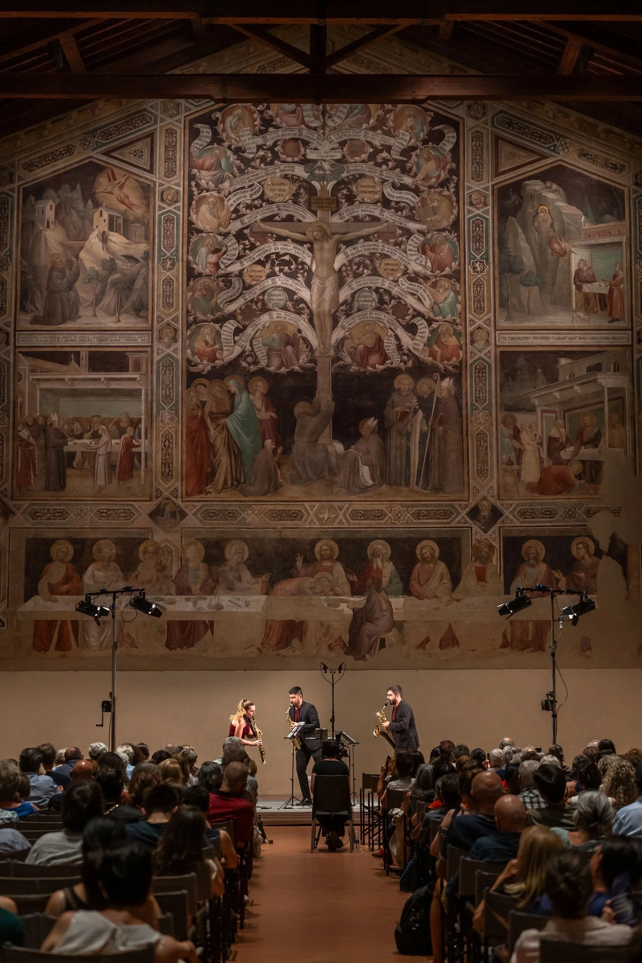 Musicians performing jazz concert in front of a large religious painting in a historic church or cathedral.