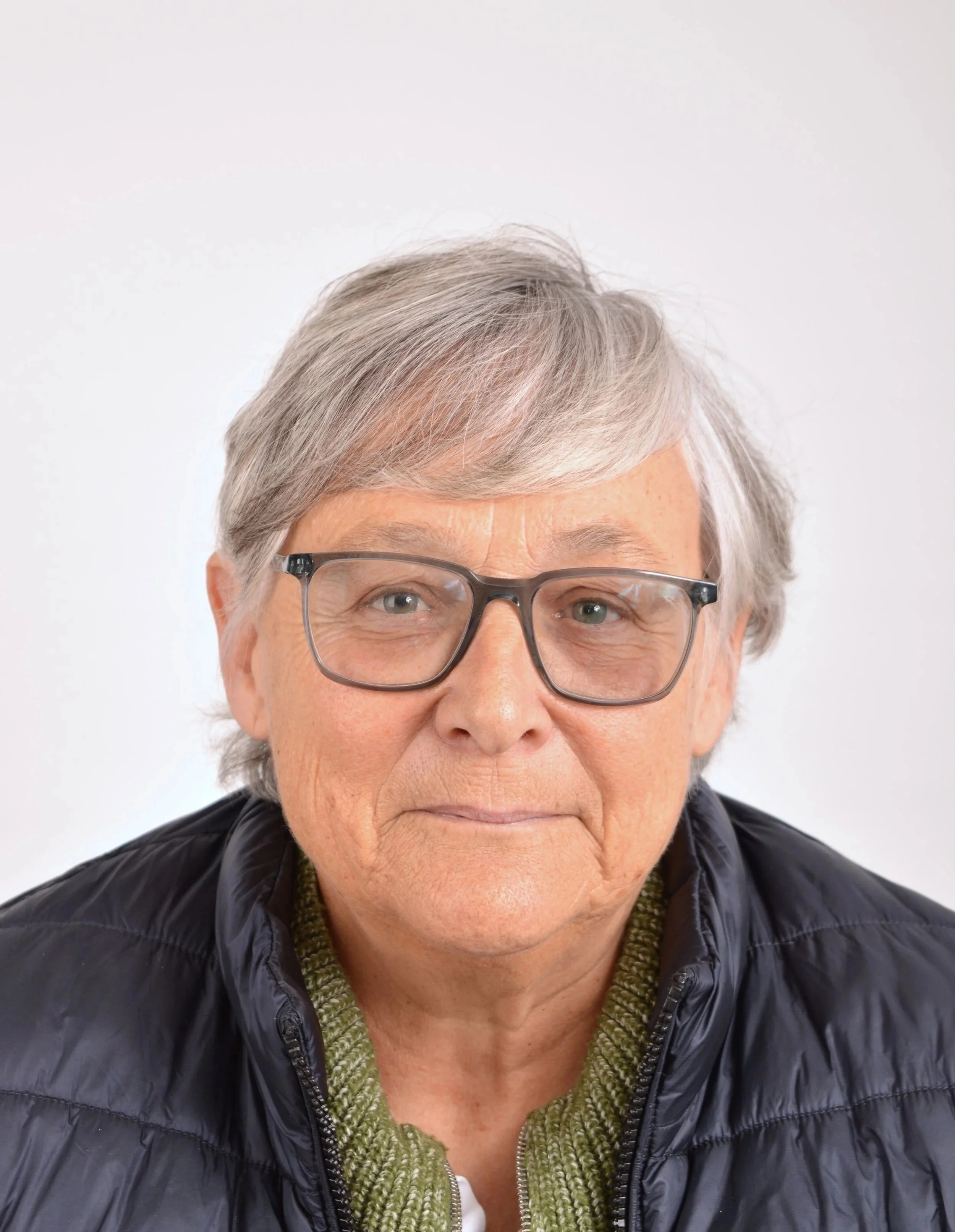 Doris Fischer-Taeschler - an older woman with short gray hair, glasses, wearing a black jacket and a green knitted sweater, against a plain white background.