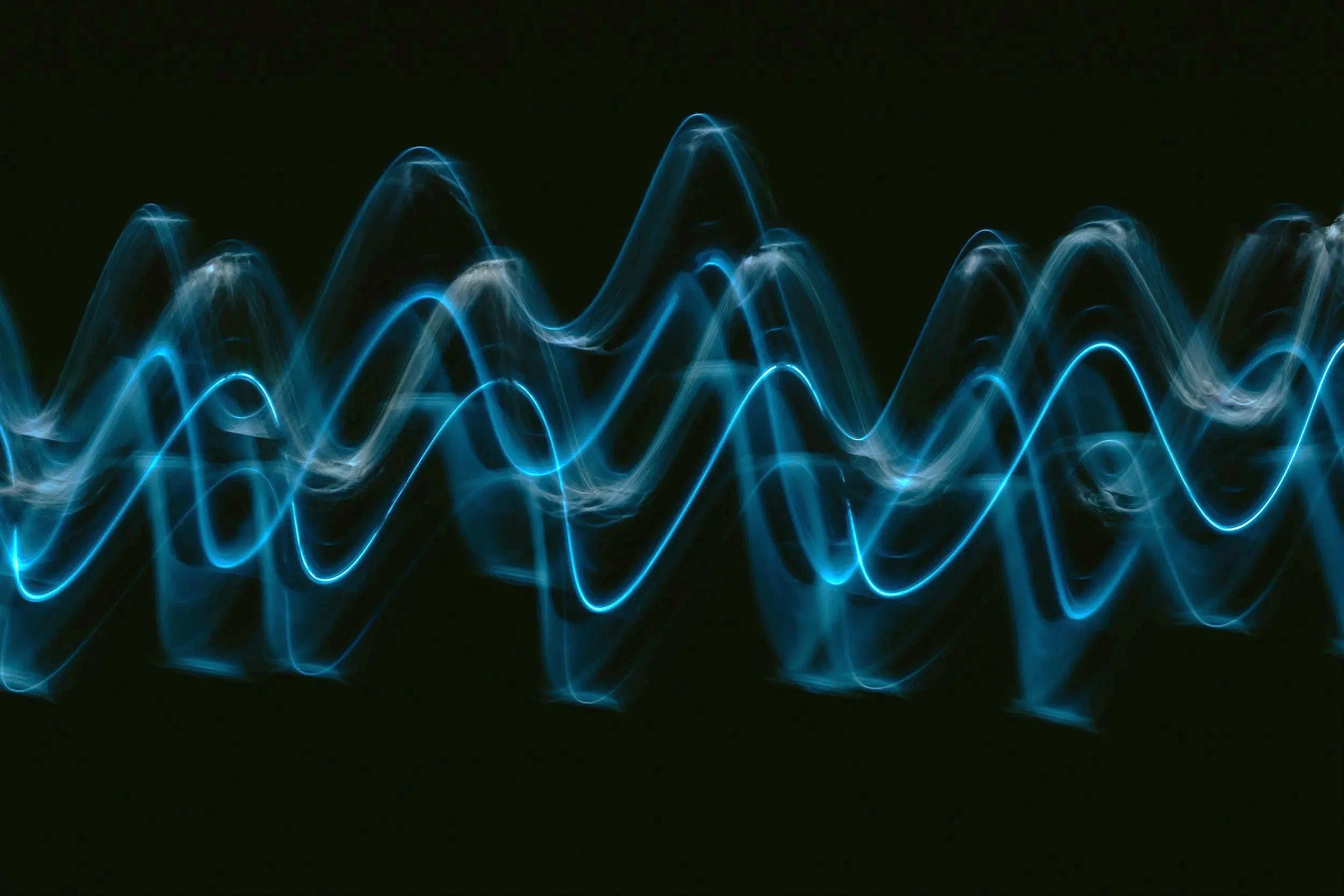 Blue light waves on a black background, resembling a waveform or sound pattern.