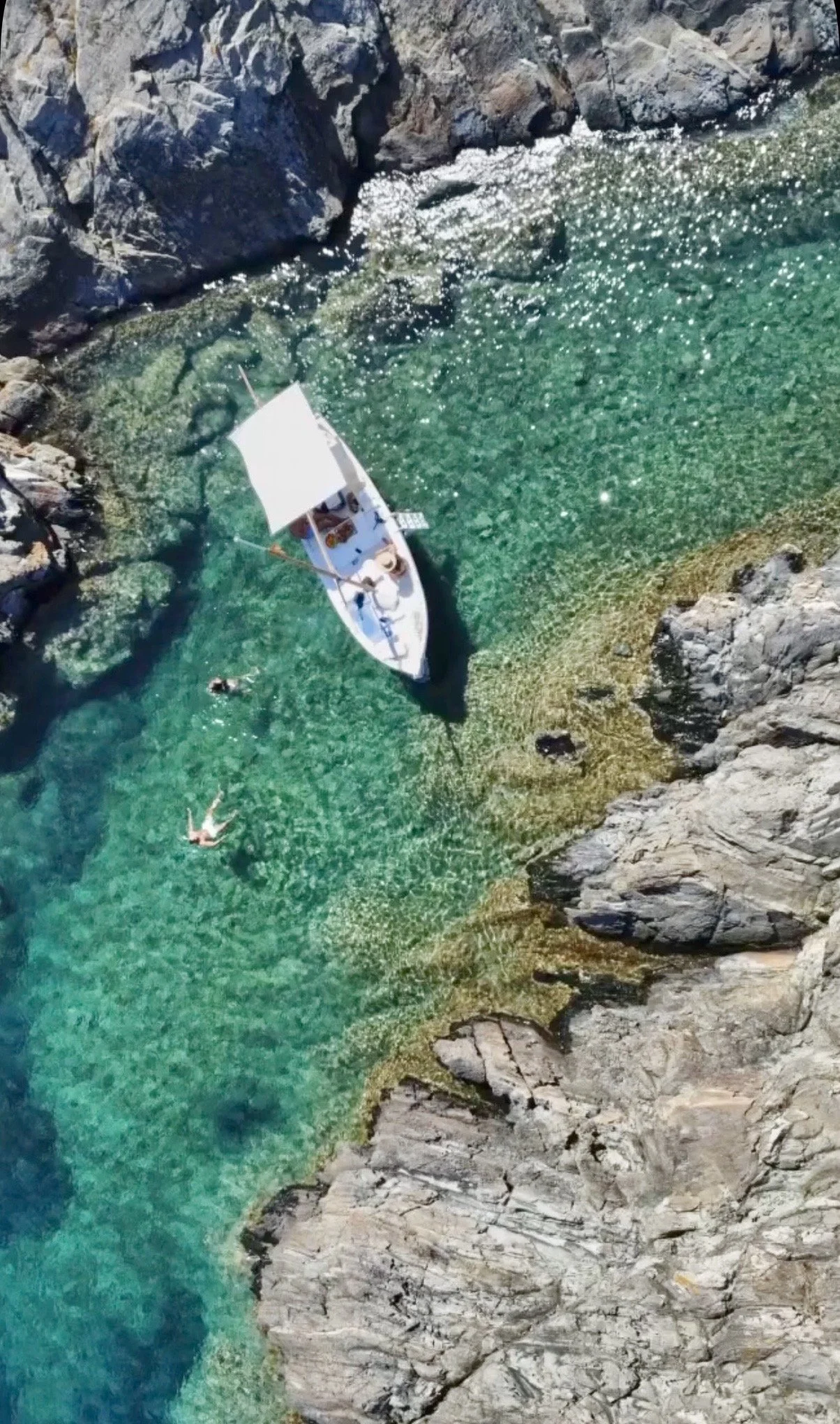Traditional wooden boat anchored in crystal clear waters of Cap de Creus during a private boat tour from Cadaqués