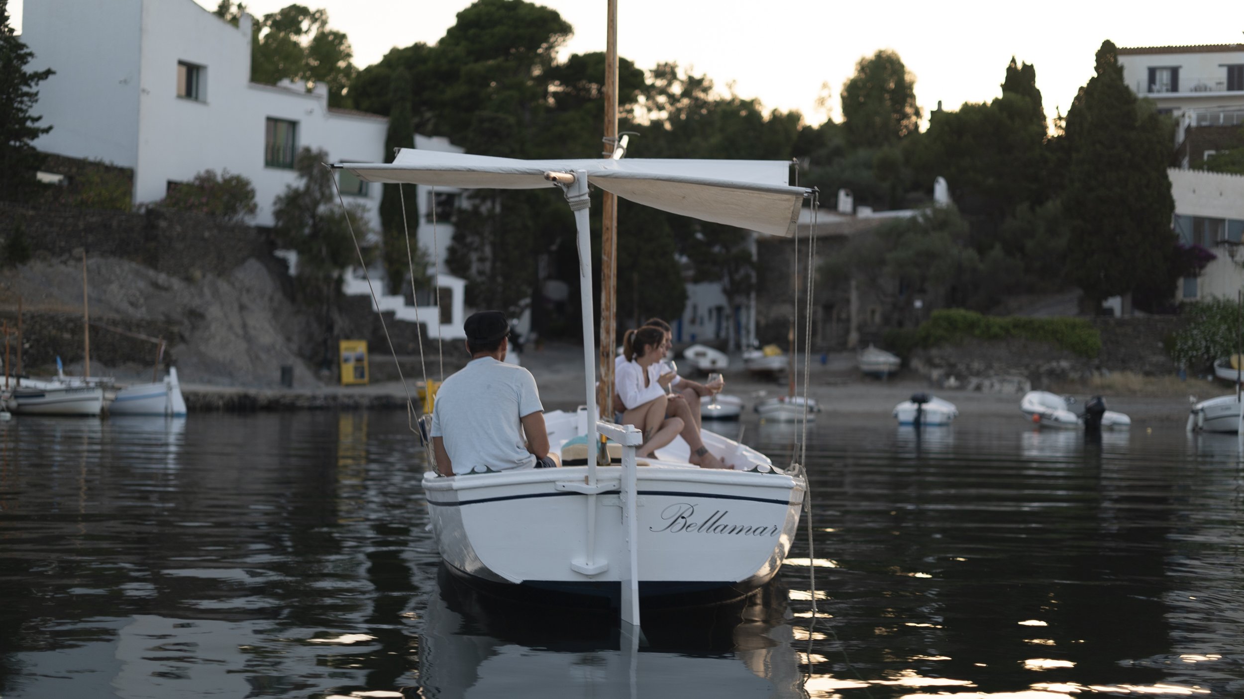 Traditional wooden boat Bellamar returning to Port Lligat in Cadaqués at sunset during a private boat tour.