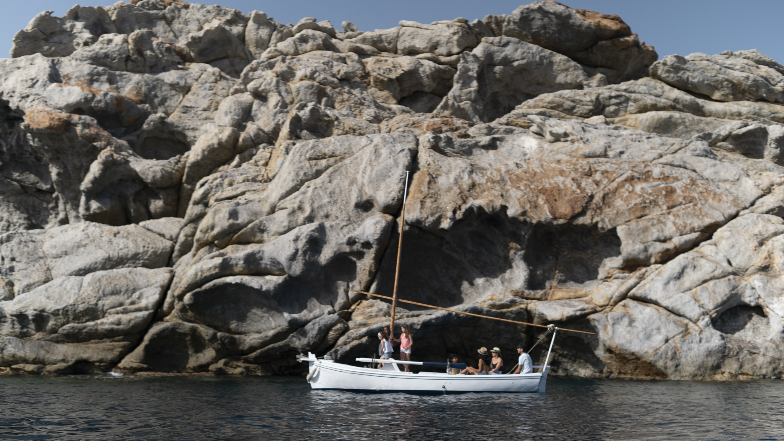 Gnarled rock formations and surreal coastline of Cap de Creus seen from a historic sailing boat.