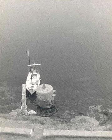Historical image of the 1931 sailboat Bellamar navigating the rugged coastline of Cap de Creus.