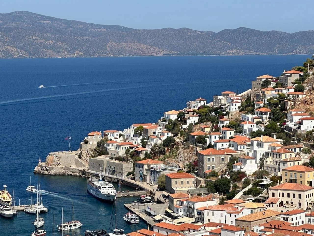 photo of hydra in greece, blue sea and white buildings on a hillside