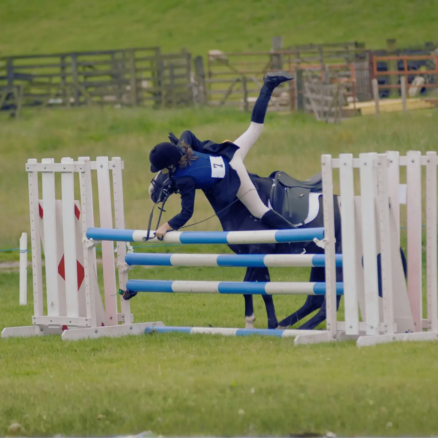 A horseback rider falling over a jump during an equestrian event.