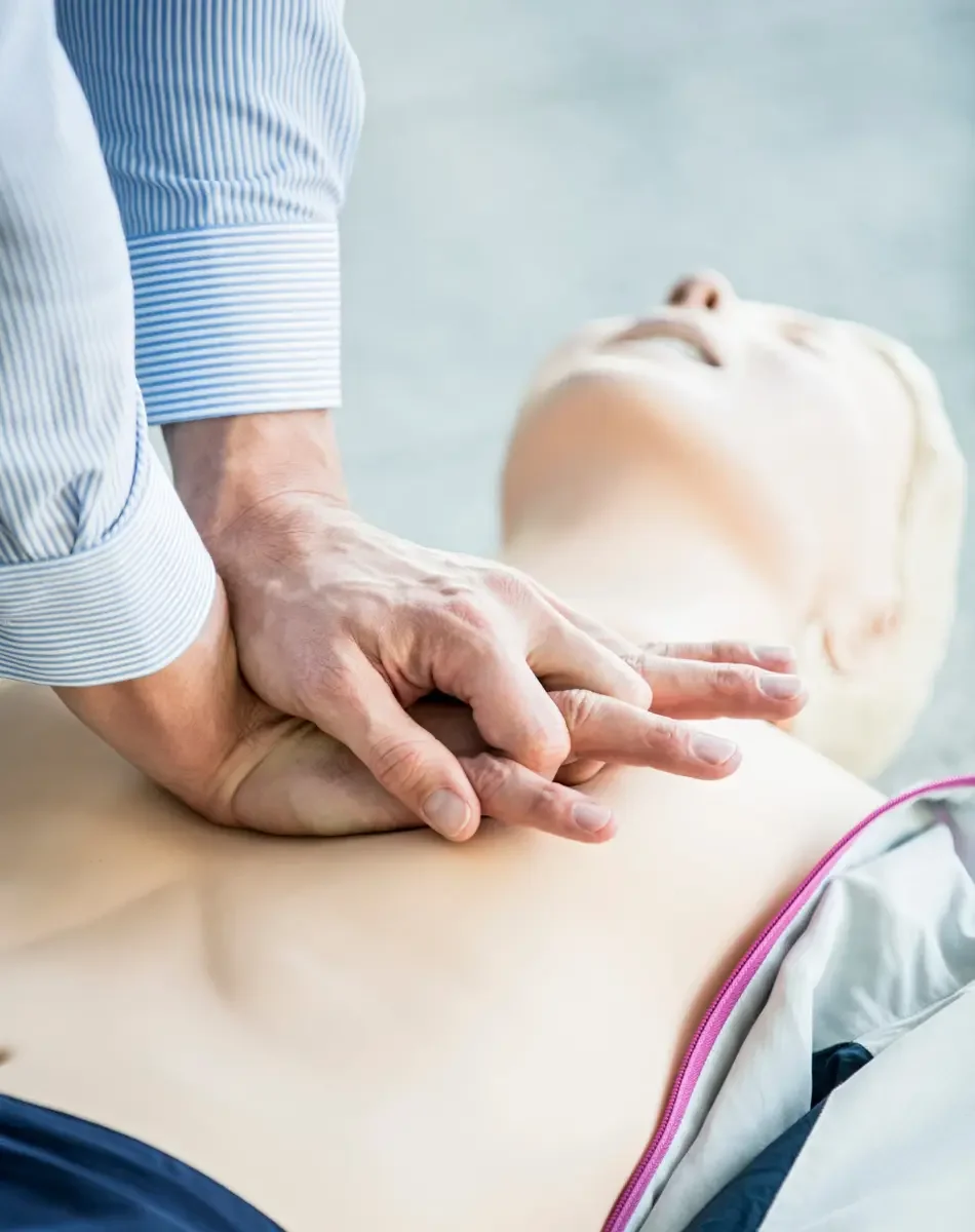 A person performs CPR on a mannequin during a training session.