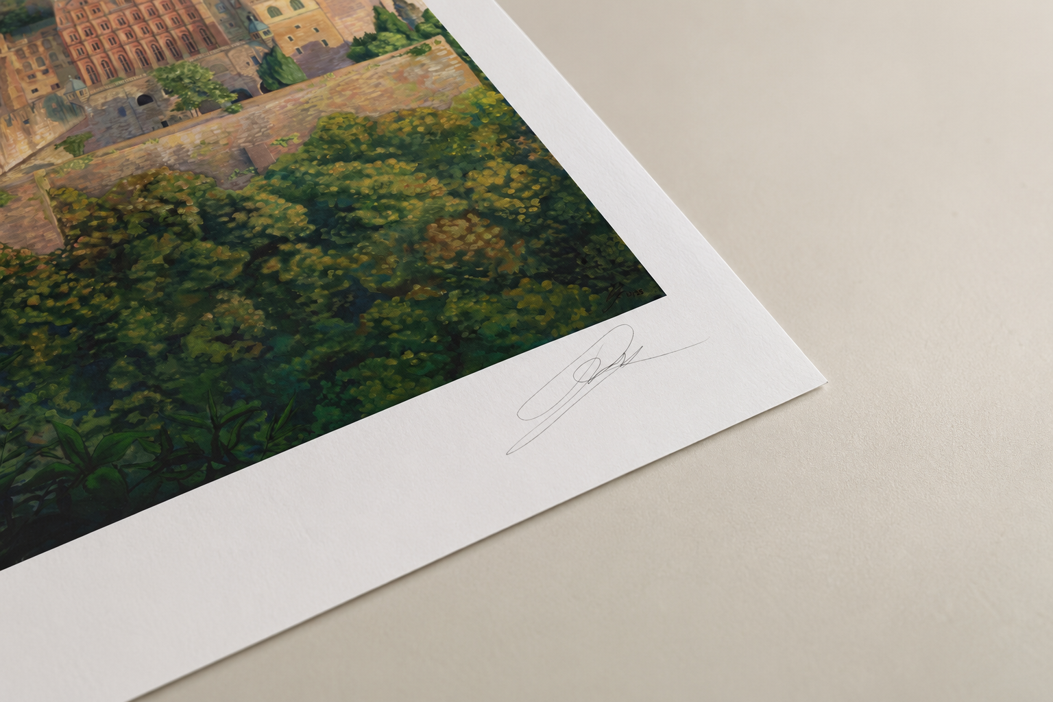 Close-up of a printed artwork featuring a cityscape with a castle in the background, surrounded by lush green trees. The artwork is signed in pencil in the bottom right corner.