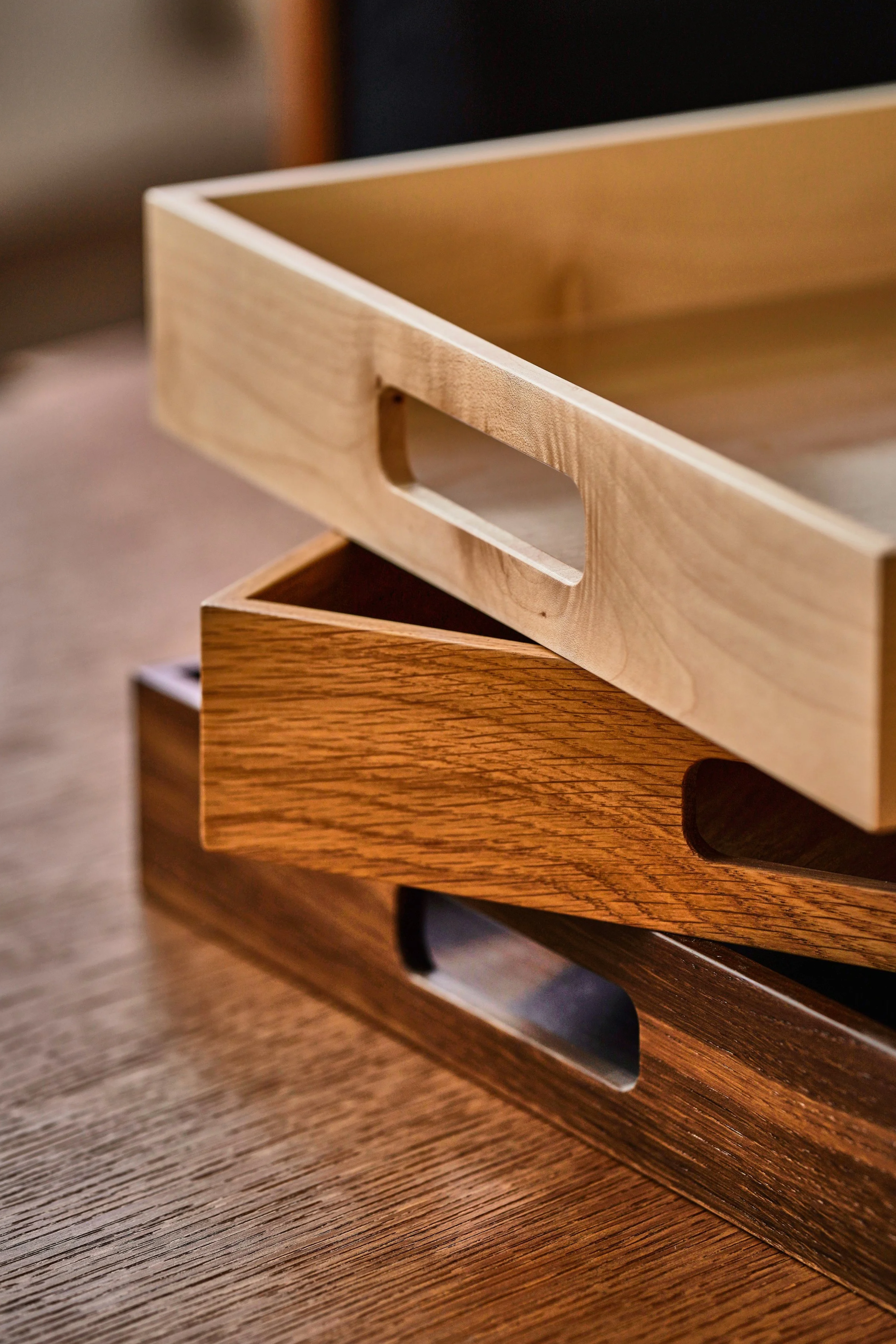 Drei hölzerne Boxen mit Grifflöchern, gestapelt auf einem Holztisch.