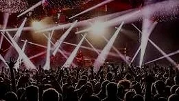 Crowd at a concert with bright stage lights and laser lights.