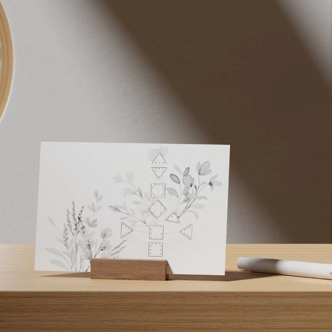 A card with geometric shape patterns and floral designs displayed on a wooden surface next to a white marker.