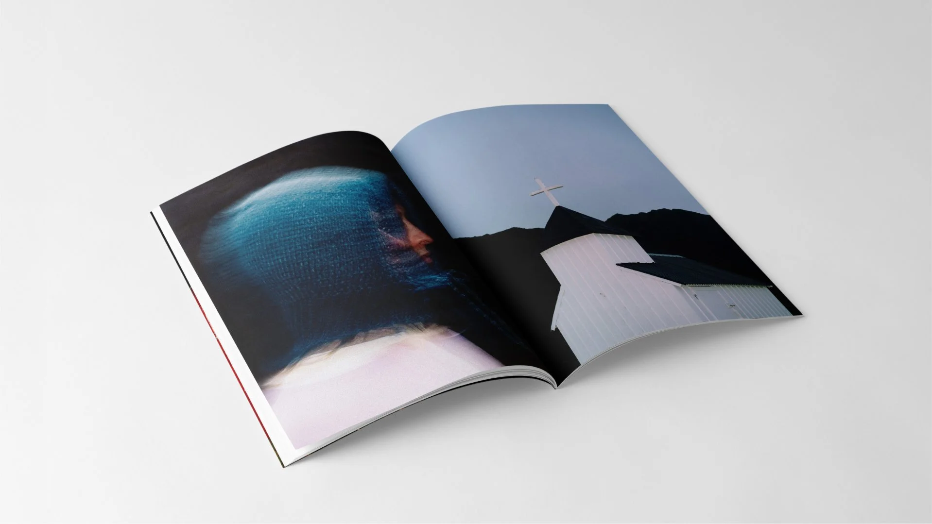 Open magazine with abstract art of a person's profile on the left and a white church with a cross on the right, against a clear sky.