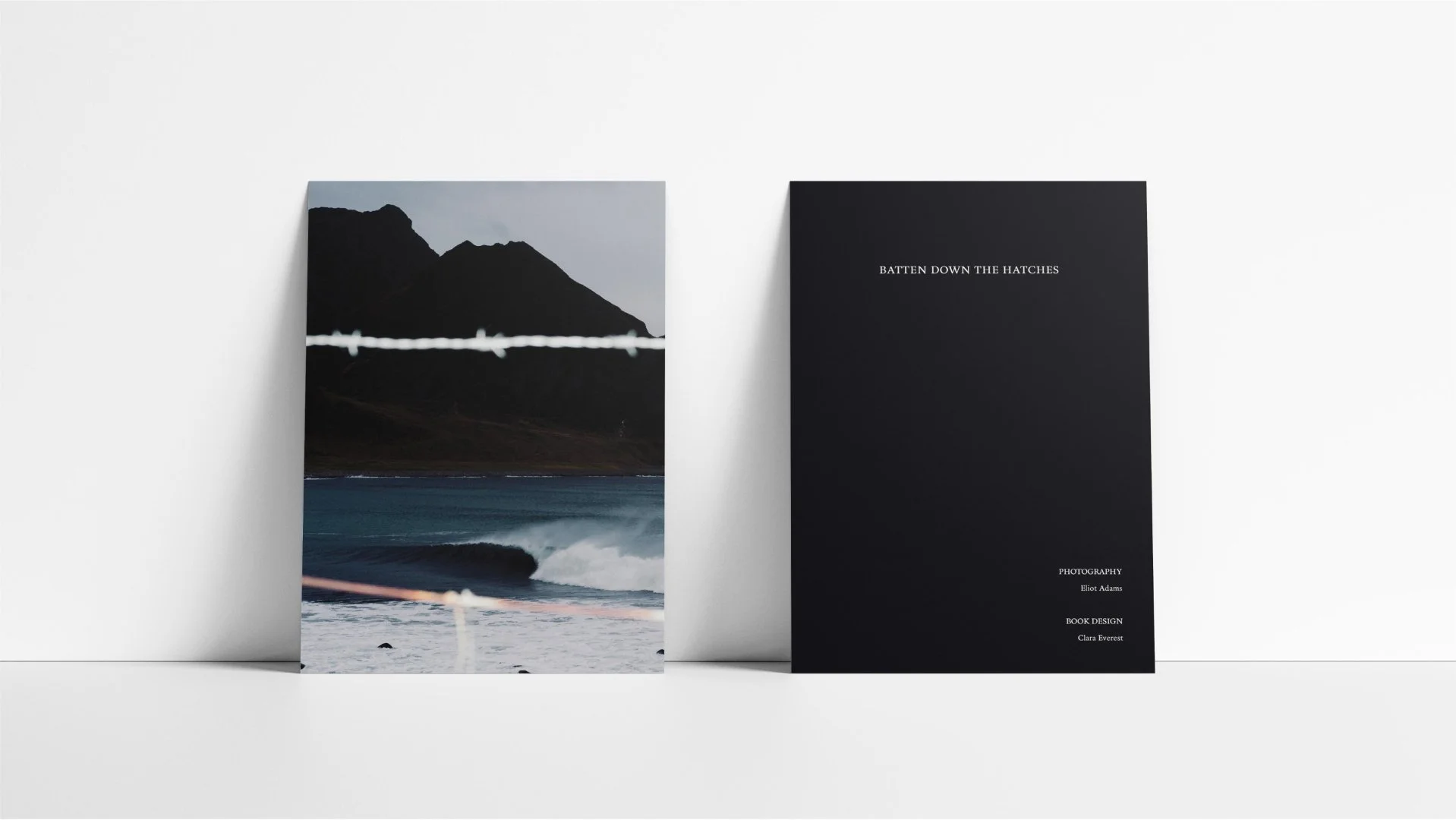 A front and back mockup of zine titled "Batten Down the Hatches" is showcasing a large landscape photograph of mountains, ocean waves, and a cloudy sky on a white background.