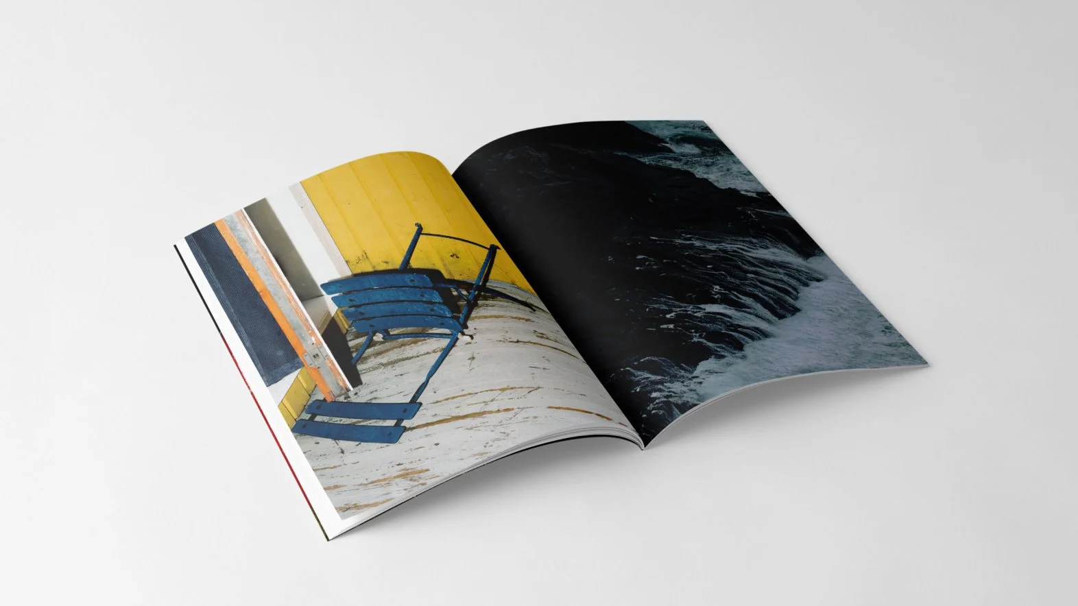 Open book showing a photo of a blue bench with yellow wall and a photo of turbulent ocean waves.
