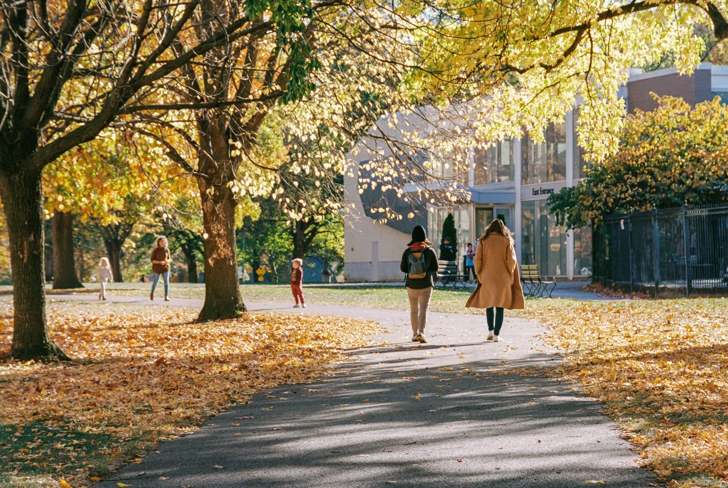 Two people walking along a peaceful, leaf-covered path in a Pittsburgh park during autumn, representing the importance of self-care and setting boundaries when healing from toxic relationships.