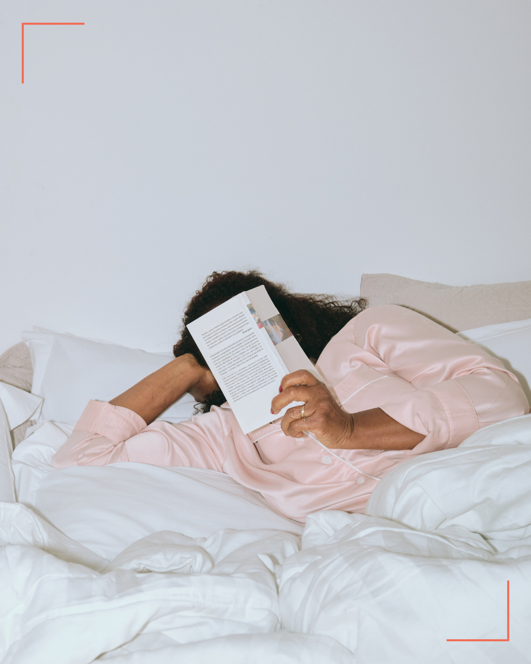 Person hiding their face behind a book in bed. PA therapist Mariah Zur explains the exhaustion of self-gaslighting.