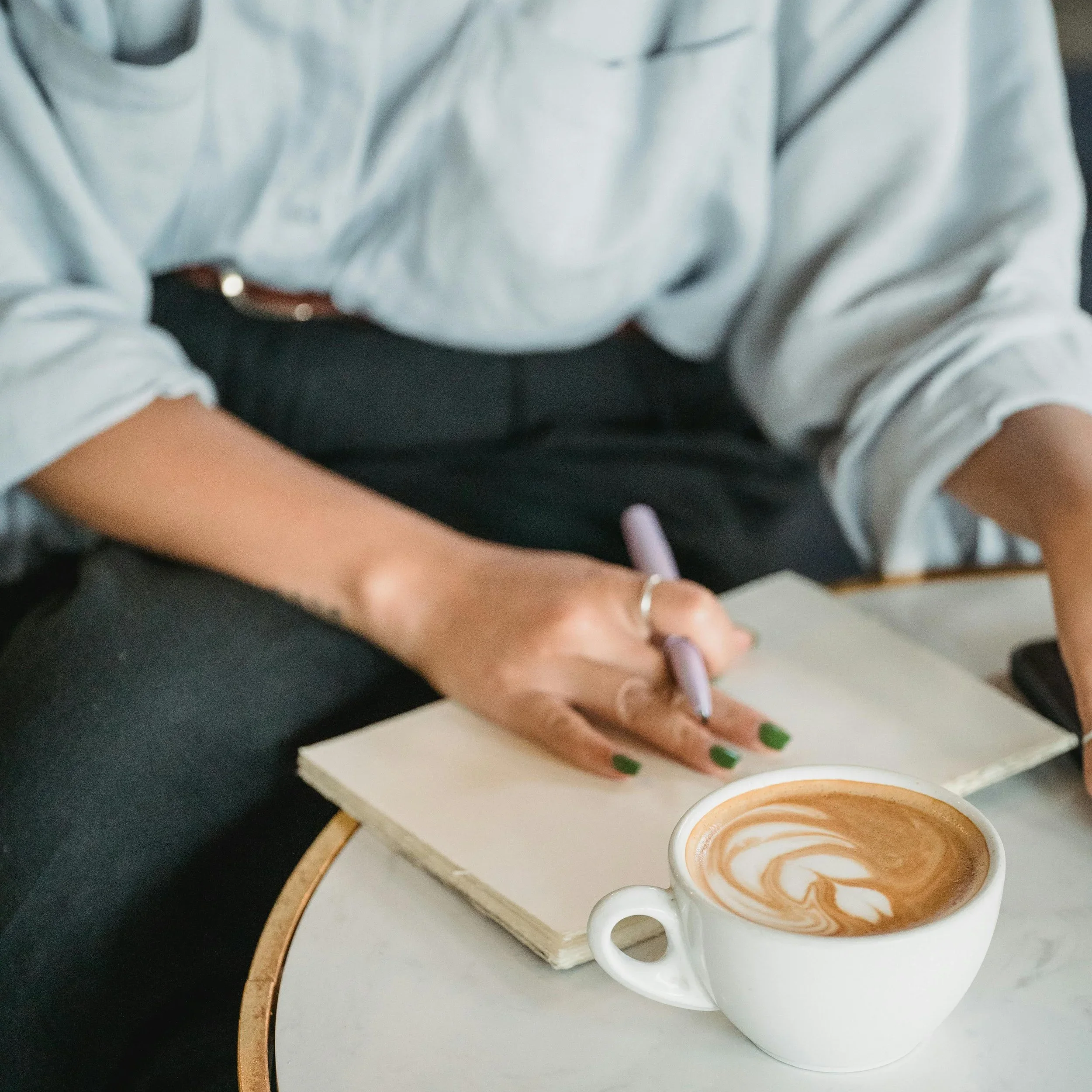 A professional in Raleigh, NC journaling with a coffee, representing the neuroplasticity integration process required after an intensive therapy session with Mariah J. Zur.